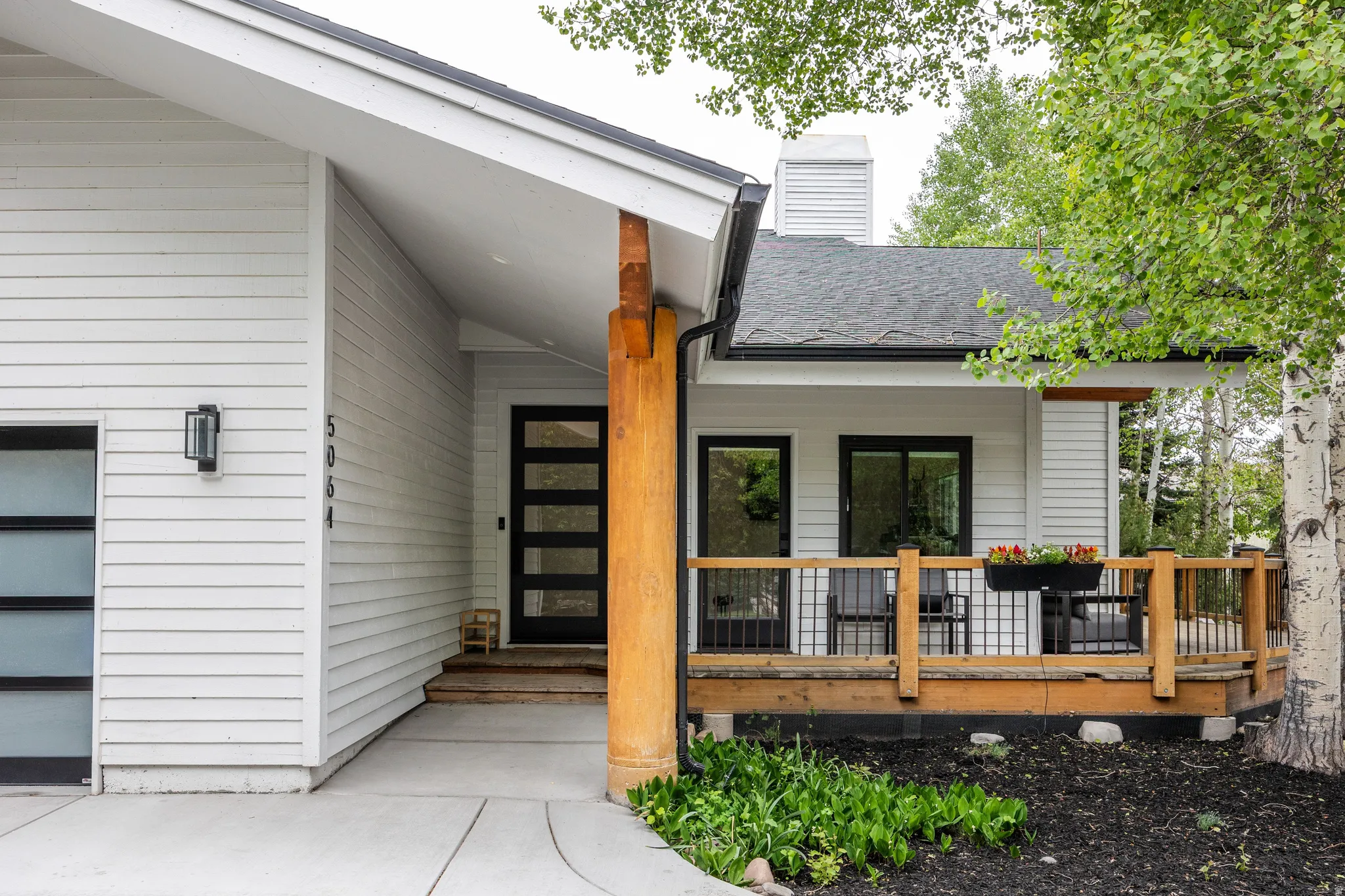 Modern exterior featuring white horizontal siding, a black shingled roof, and a contemporary front door with horizontal glass panels