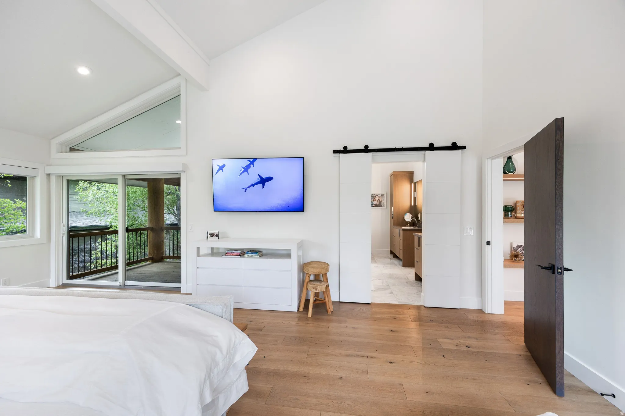 Vaulted ceilings highlight this bright room featuring wood-finish flooring