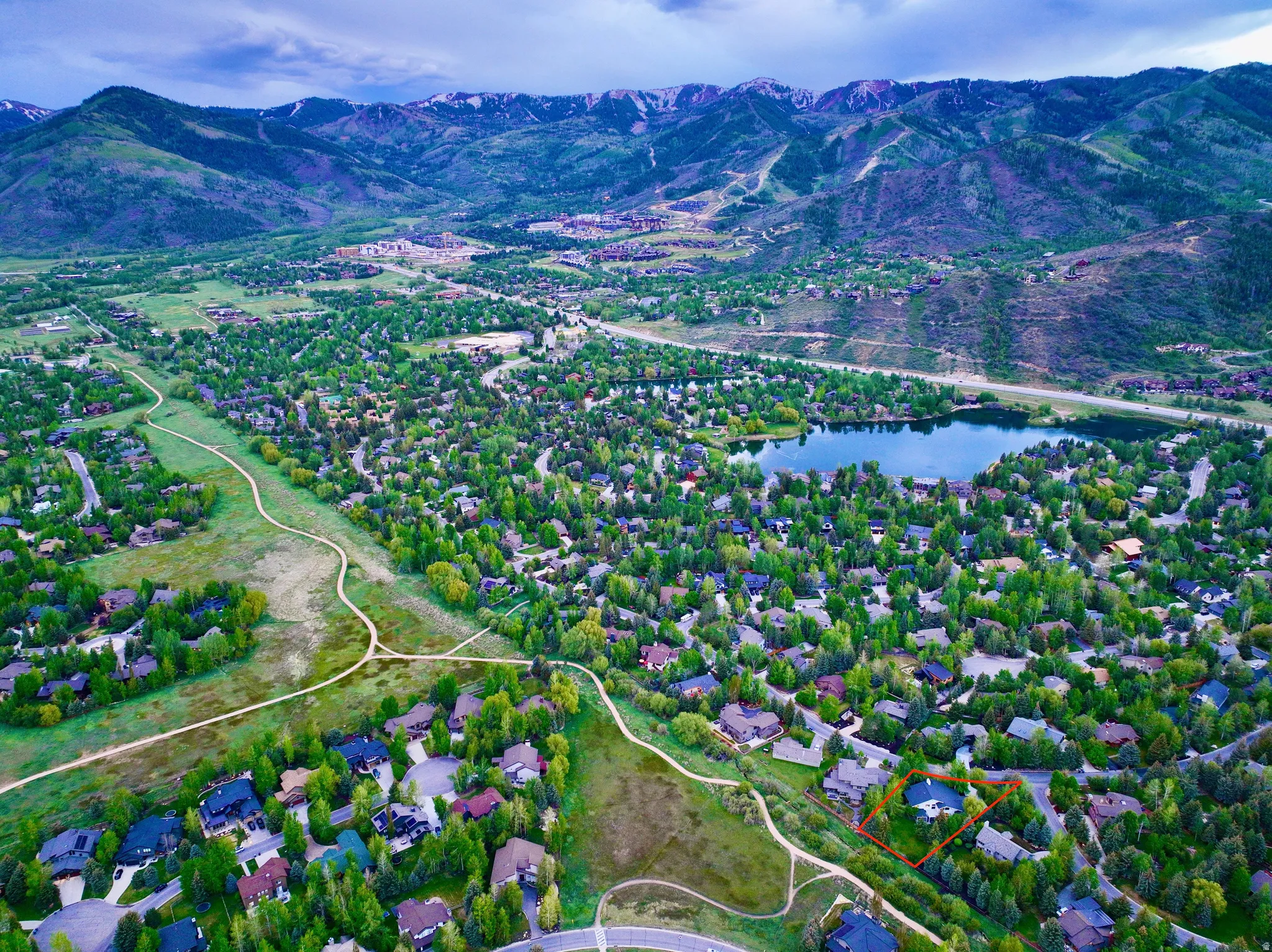 Aerial perspective showcasing a residential community nestled among mature trees and green spaces, featuring a prominent lake