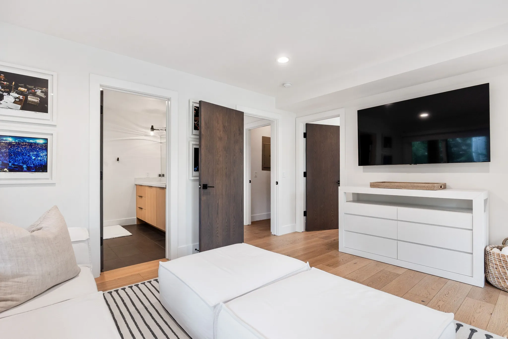 Hardwood flooring and recessed lighting illuminate this bright interior, featuring a built-in entertainment console