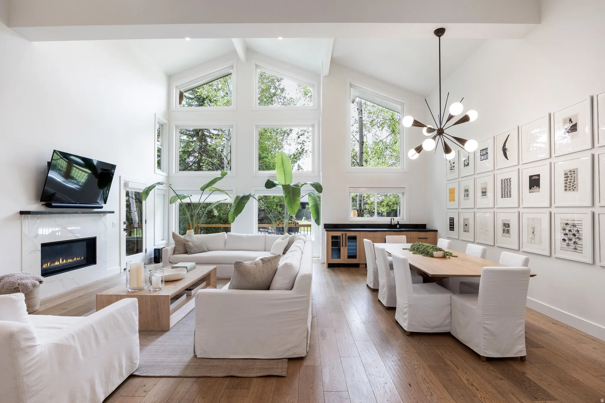 Vaulted ceilings featuring expansive windows, wood-finish flooring, and a contemporary fireplace with a marble-look surround