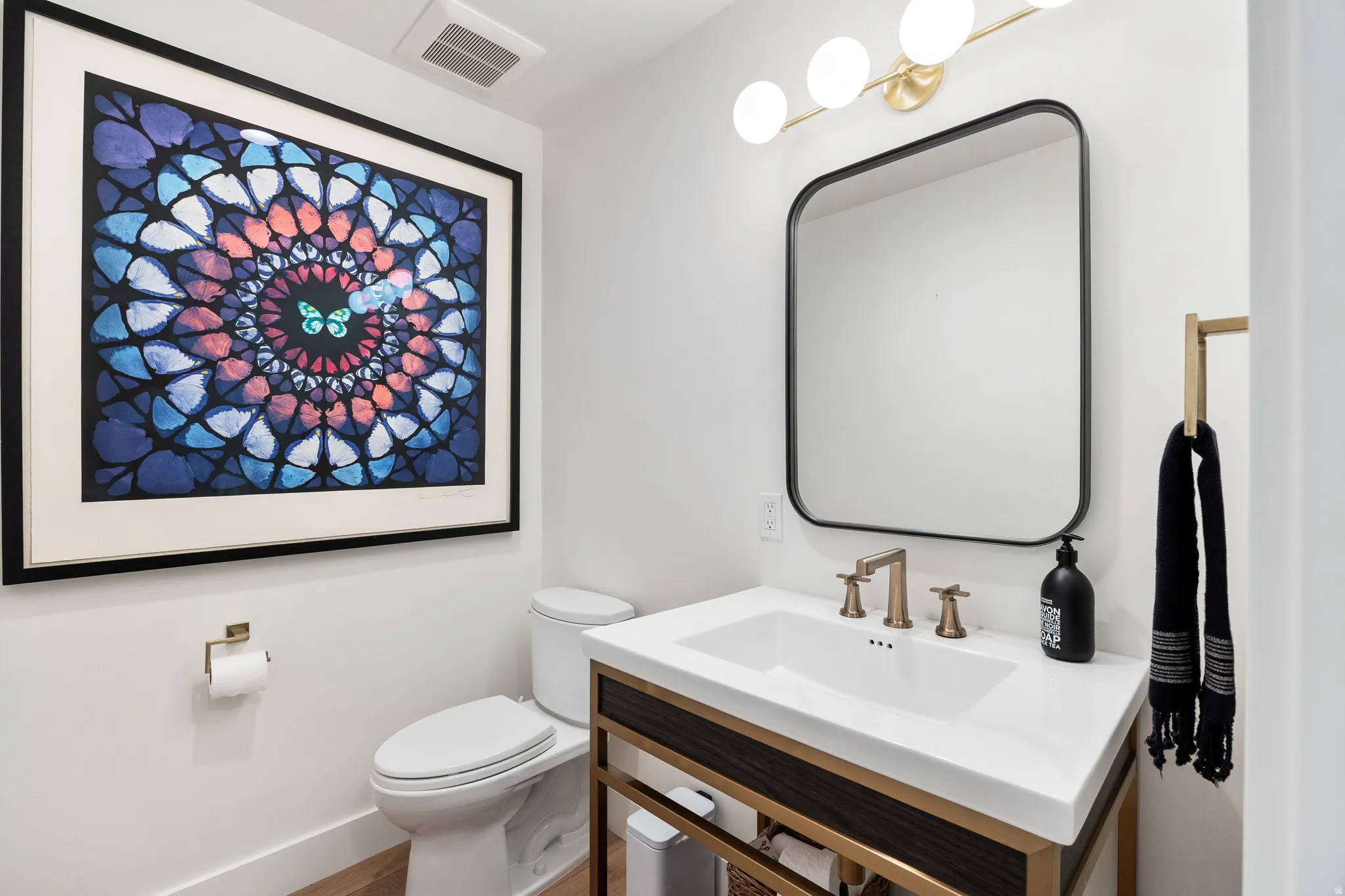 White vanity with an integrated rectangular sink and bronze-finish faucet, framed by a matte black mirror and overhead globe lighting