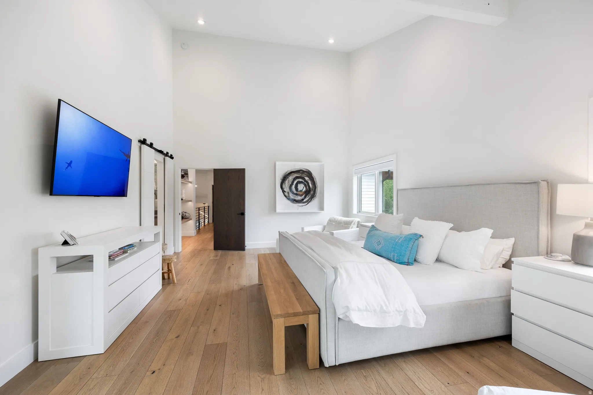 Vaulted ceilings enhance this space featuring wood-finish flooring and crisp white walls