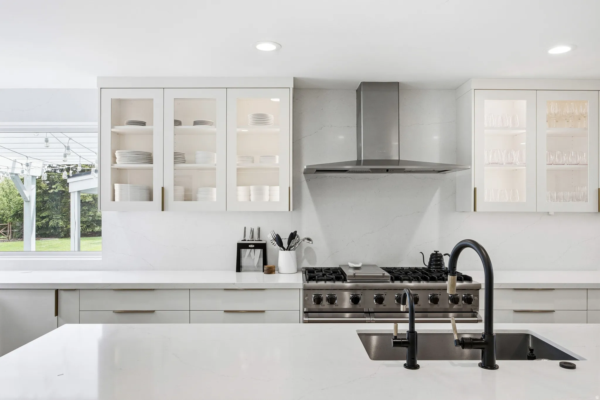 Kitchen featuring a stainless steel range with a professional-grade hood, white quartz countertops, and a large sink with a matte black faucet