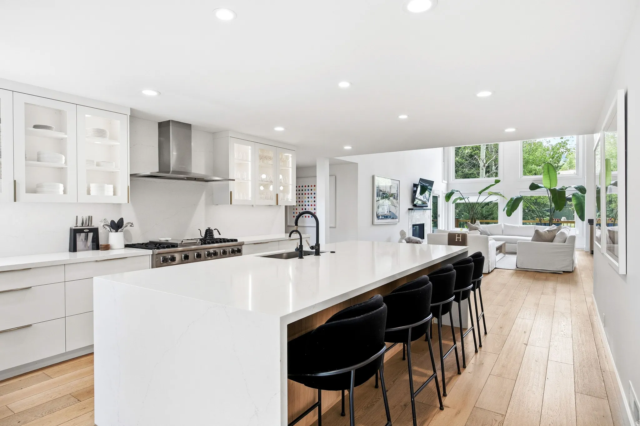 Open-concept kitchen featuring a large island with seating, stainless steel appliances, white cabinetry, and wood-finish flooring