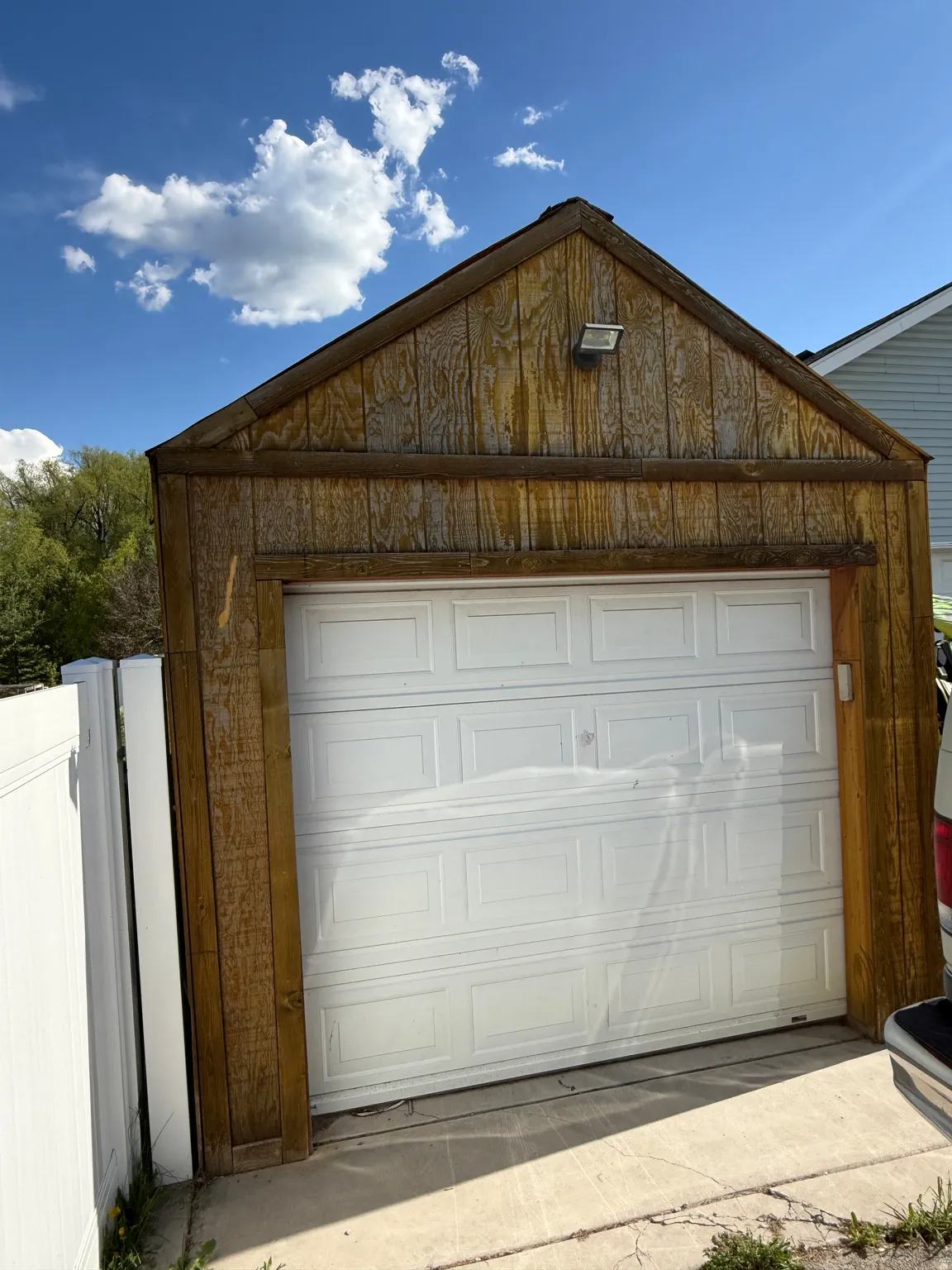 Detached garage featuring wood-paneled siding and a white paneled garage door