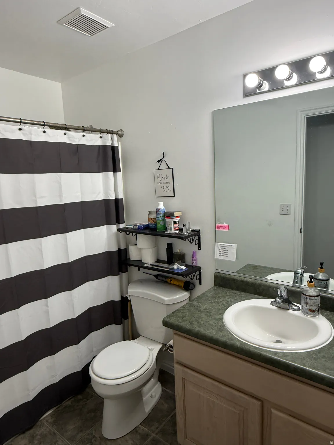 Bathroom featuring an integrated sink, laminate countertop, vanity lighting, and wall-mounted shelving