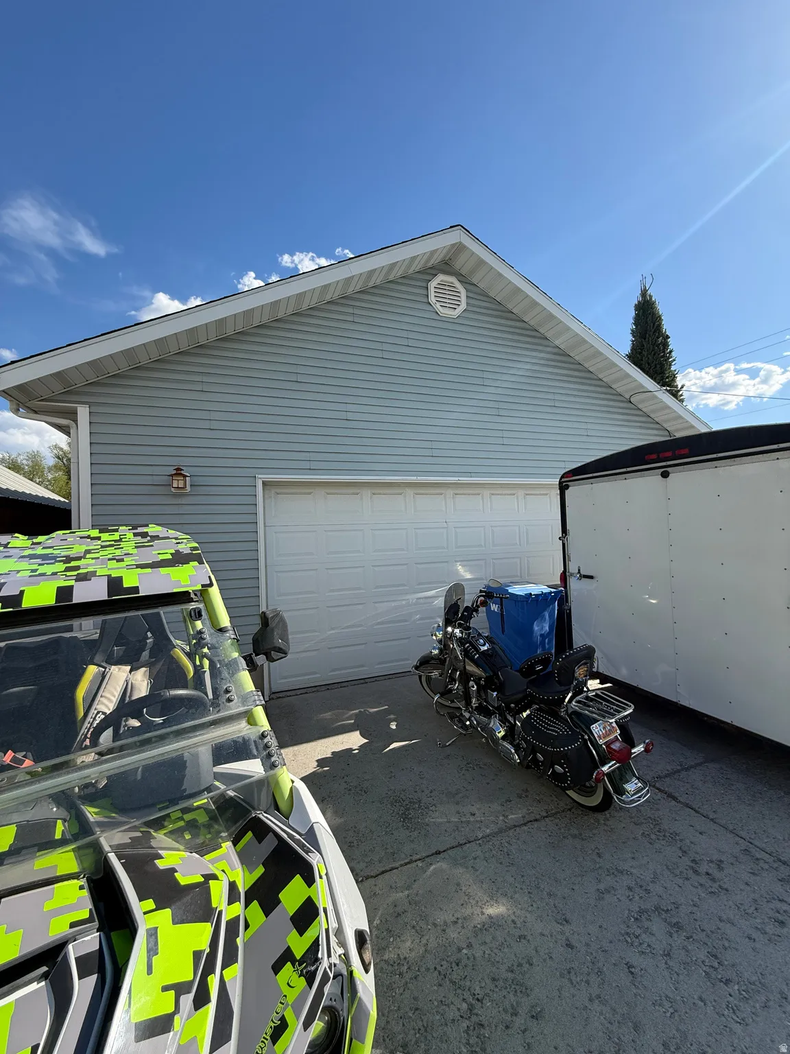 Attached two-car garage with light blue siding, a white overhead door, and an exterior wall lantern