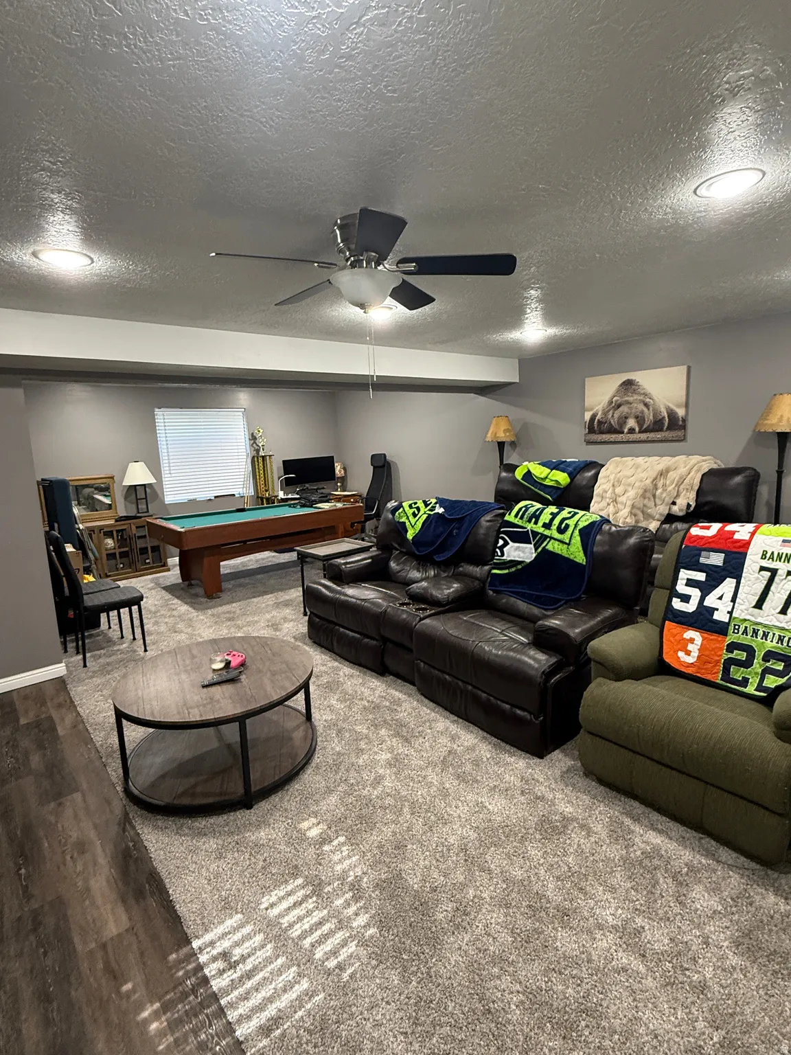 Spacious recreation area featuring a combination of wood-finish flooring and light-toned carpeting, recessed lighting, and a ceiling fan