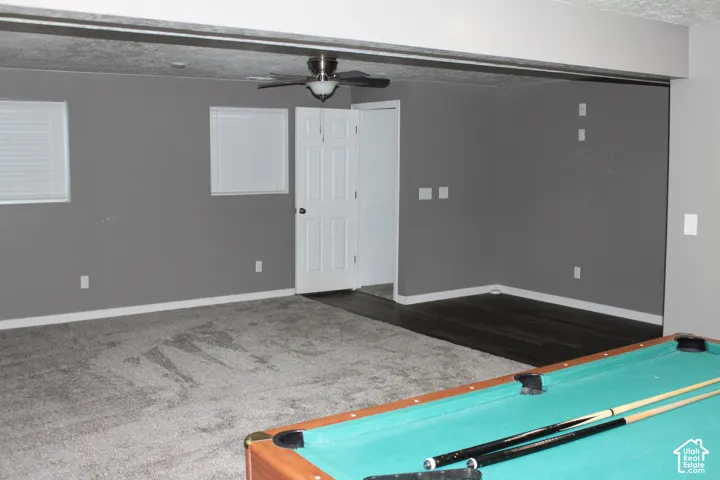 Spacious room featuring a mix of grey carpeting and dark wood-finish flooring