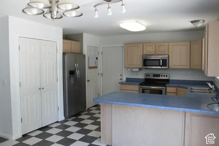 Kitchen featuring light wood cabinetry, stainless steel appliances, blue countertops, and checkerboard floor tiles