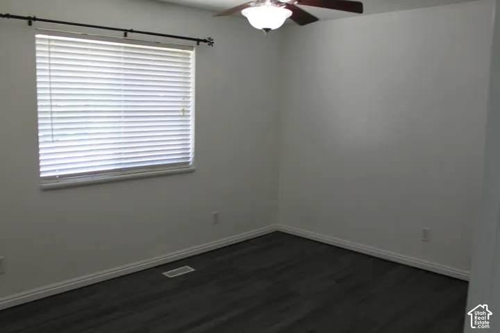Room featuring dark wood-finish flooring, crisp white baseboards, and neutral wall tones