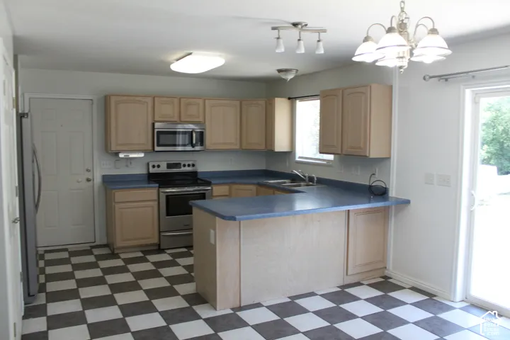 Kitchen featuring checkerboard flooring, light wood-finish cabinetry, blue countertops, and stainless steel appliances