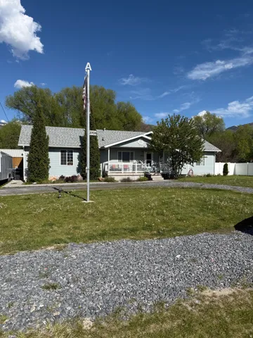 Single-story residence featuring light blue siding, a gray shingle roof, and a covered front porch with white railing