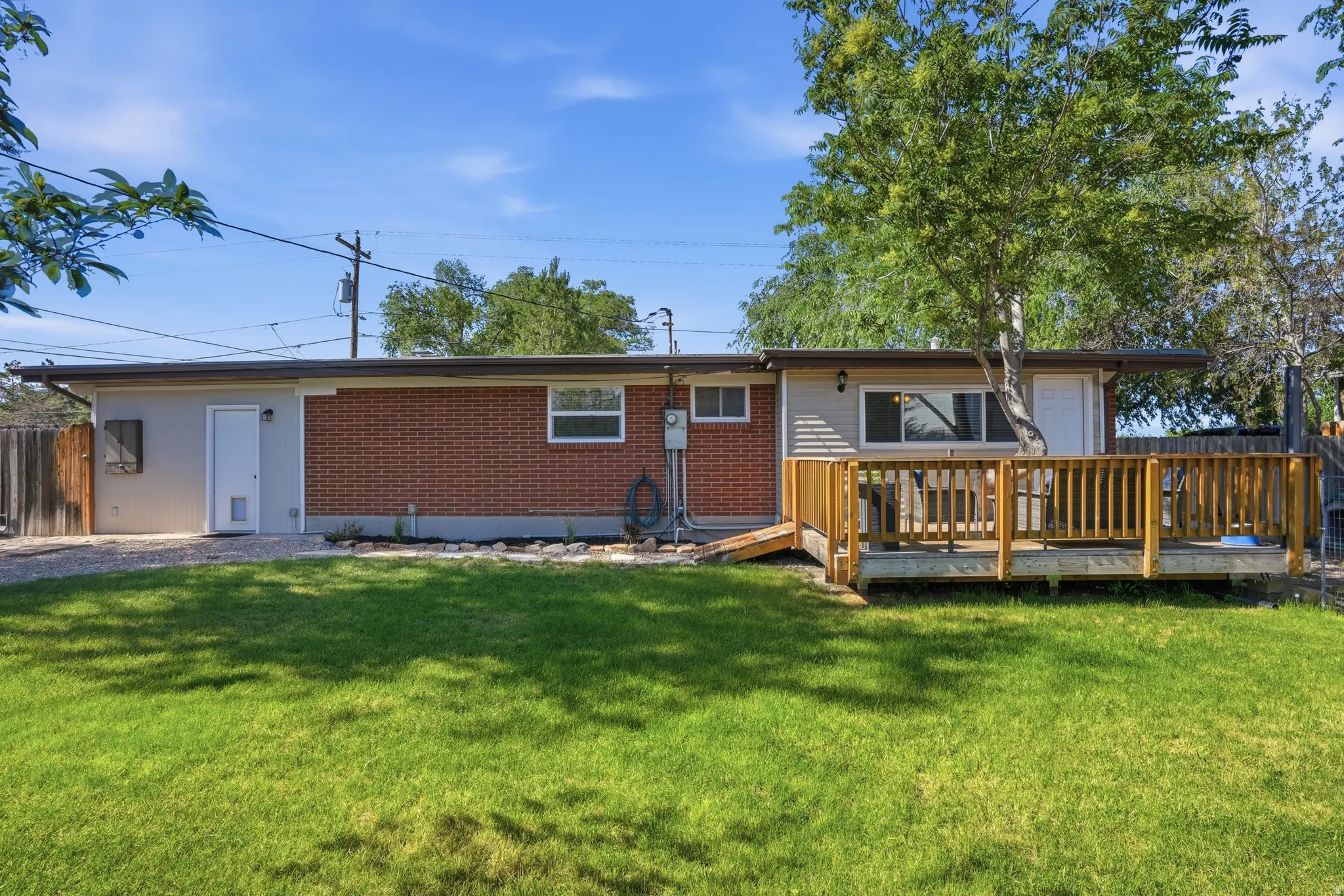 Expansive backyard with a manicured lawn, a wood deck with railings, and mature trees