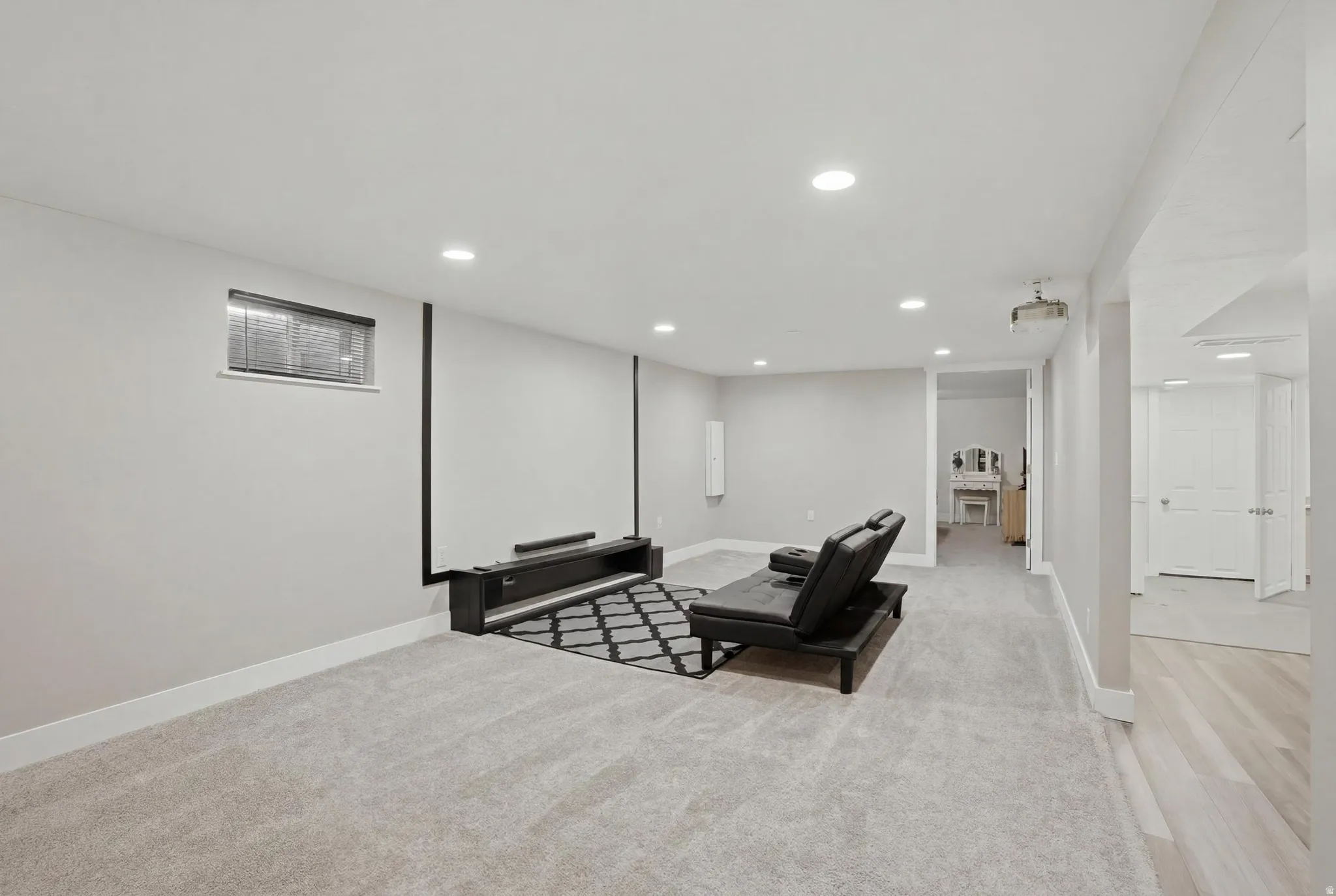 Spacious room with recessed lighting, light gray carpeting, and a contrasting black accent wall feature