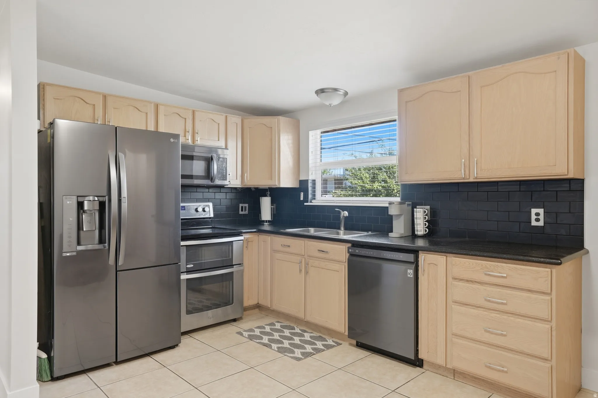 Kitchen featuring wood cabinetry, dark countertops, and a black subway tile backsplash