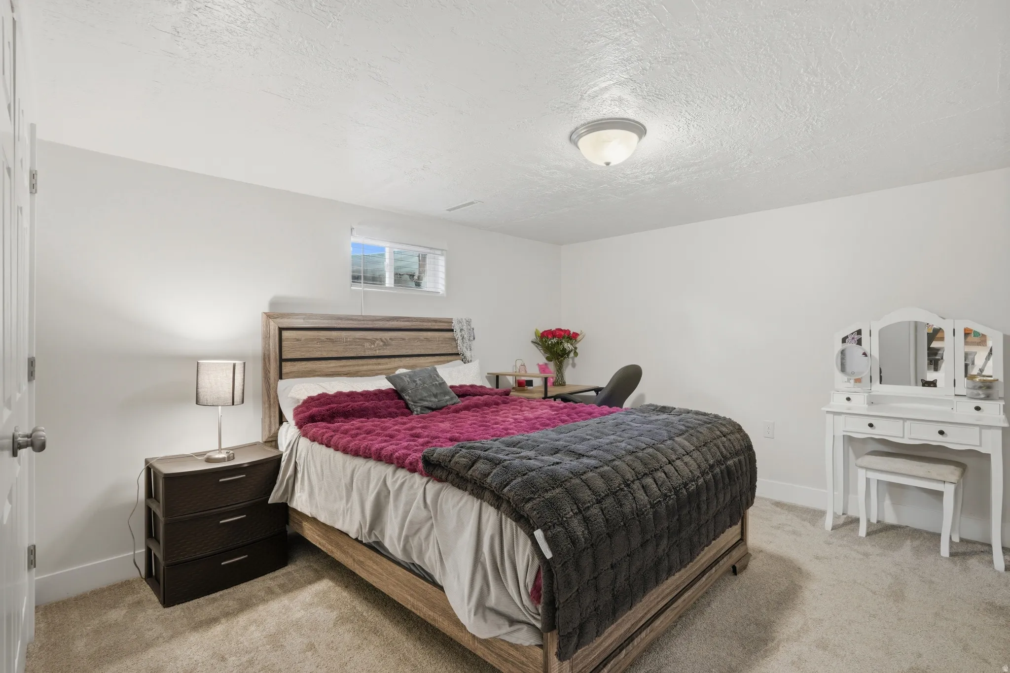 Bedroom featuring light-toned carpeting, white walls, and a window with horizontal blinds