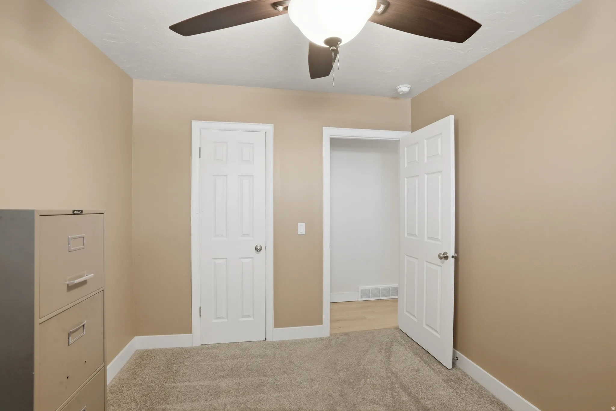 Interior room featuring neutral wall color, textured carpet flooring, and white baseboards