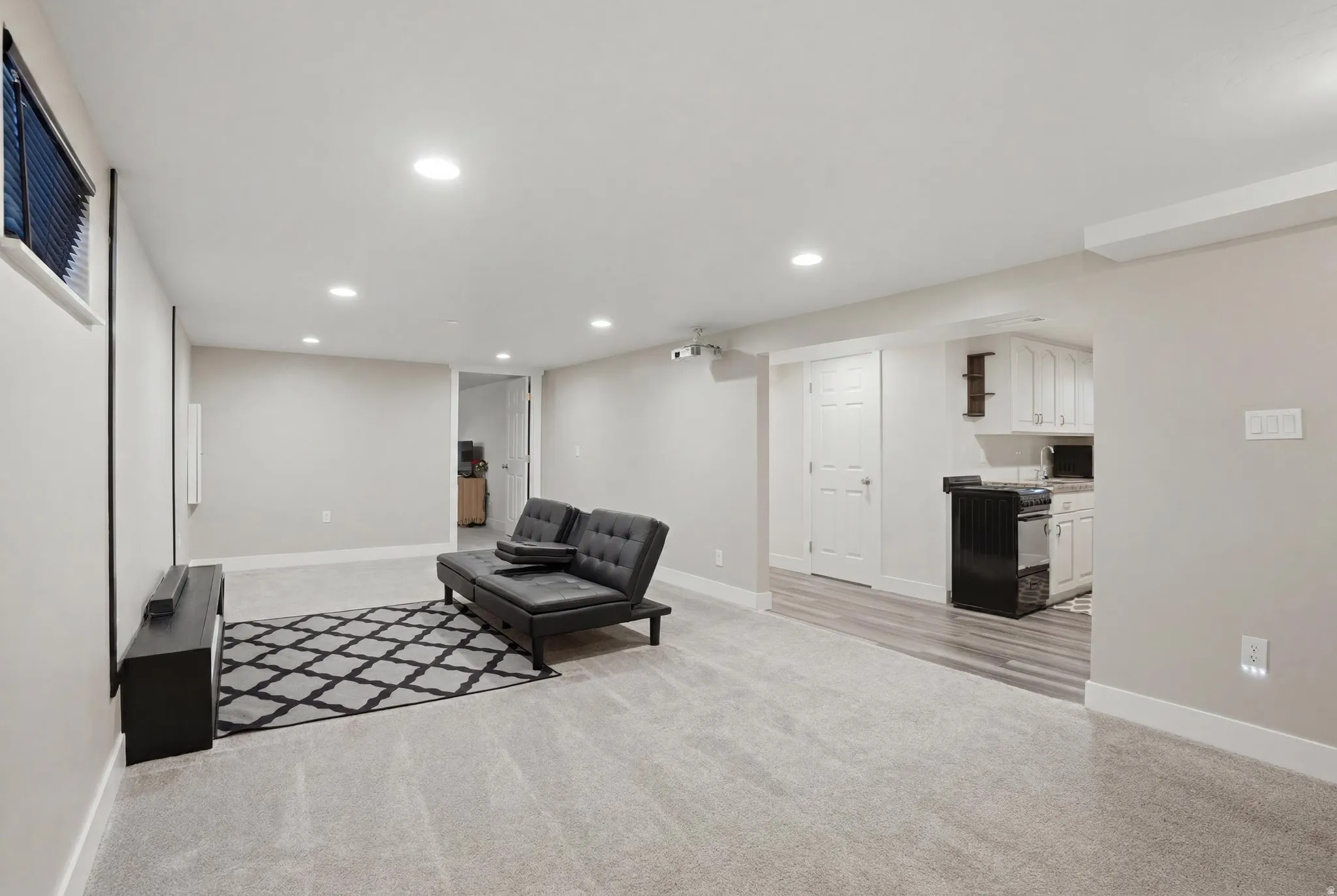 Expansive carpeted room with recessed lighting, offering a flexible layout