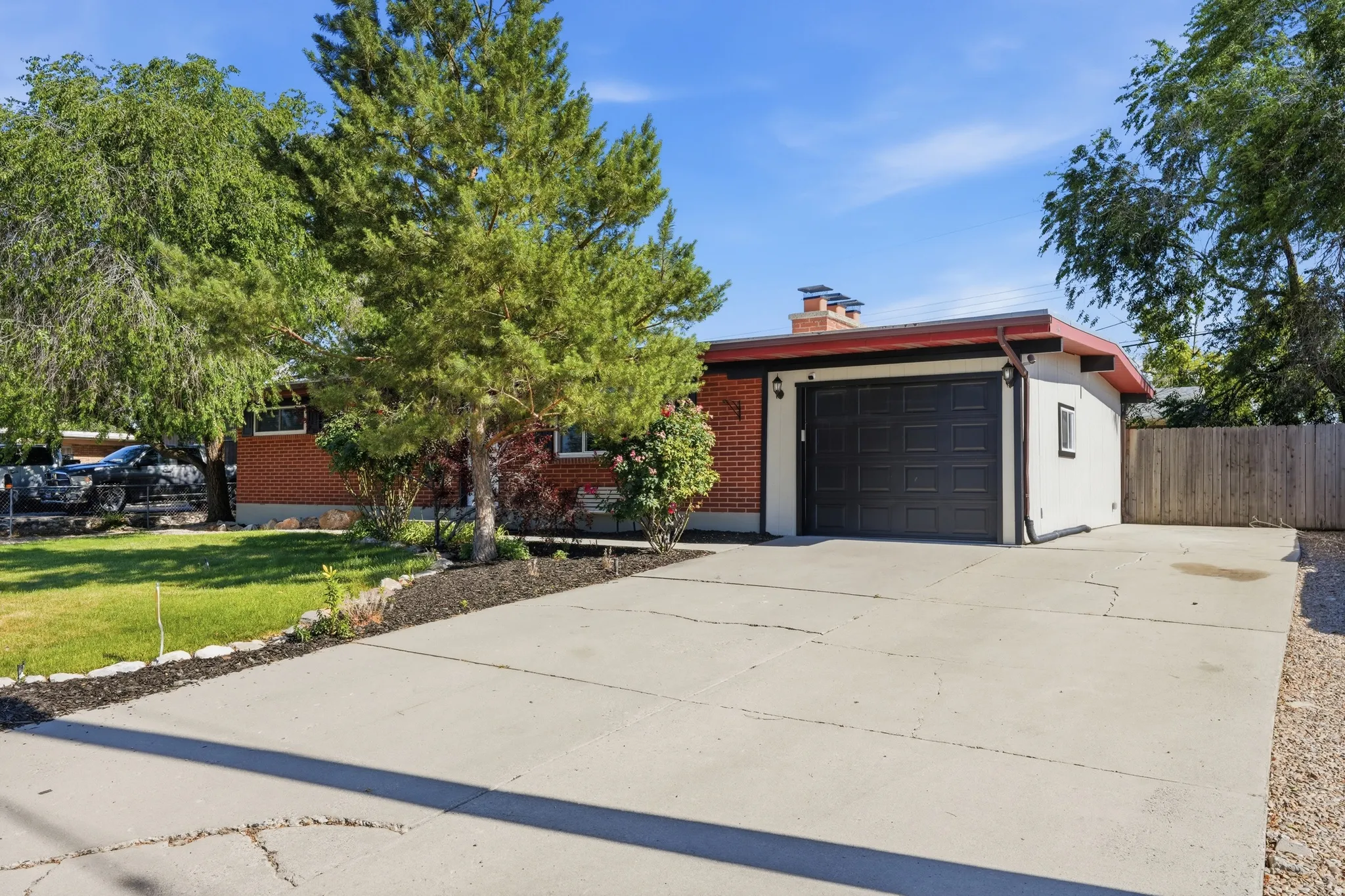 Exterior facade featuring red brick and white stucco, a dark garage door, and a concrete driveway