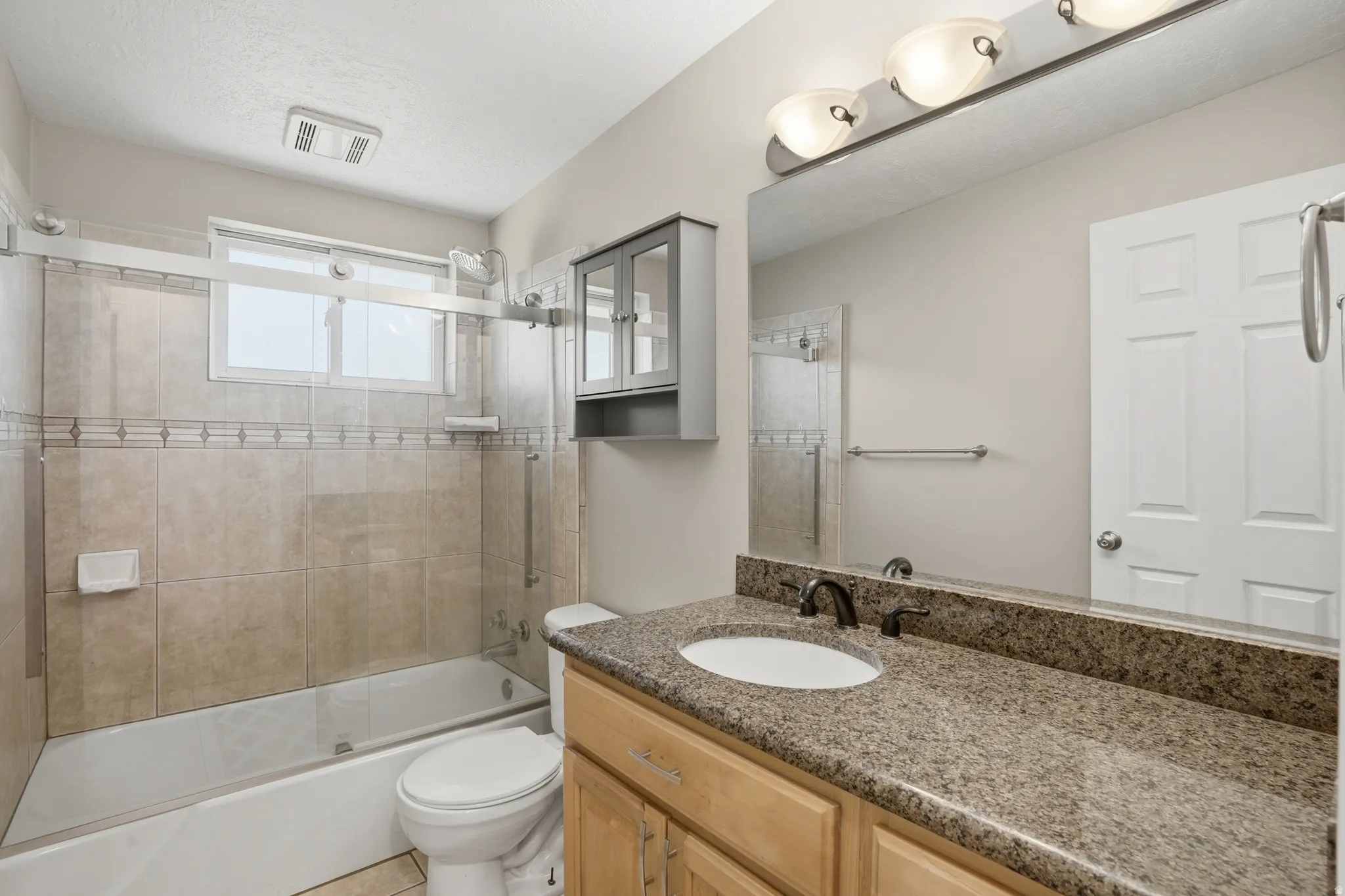 Bathroom featuring a granite-finish countertop vanity with an undermount sink, bronze-finish faucet, and a large mirror