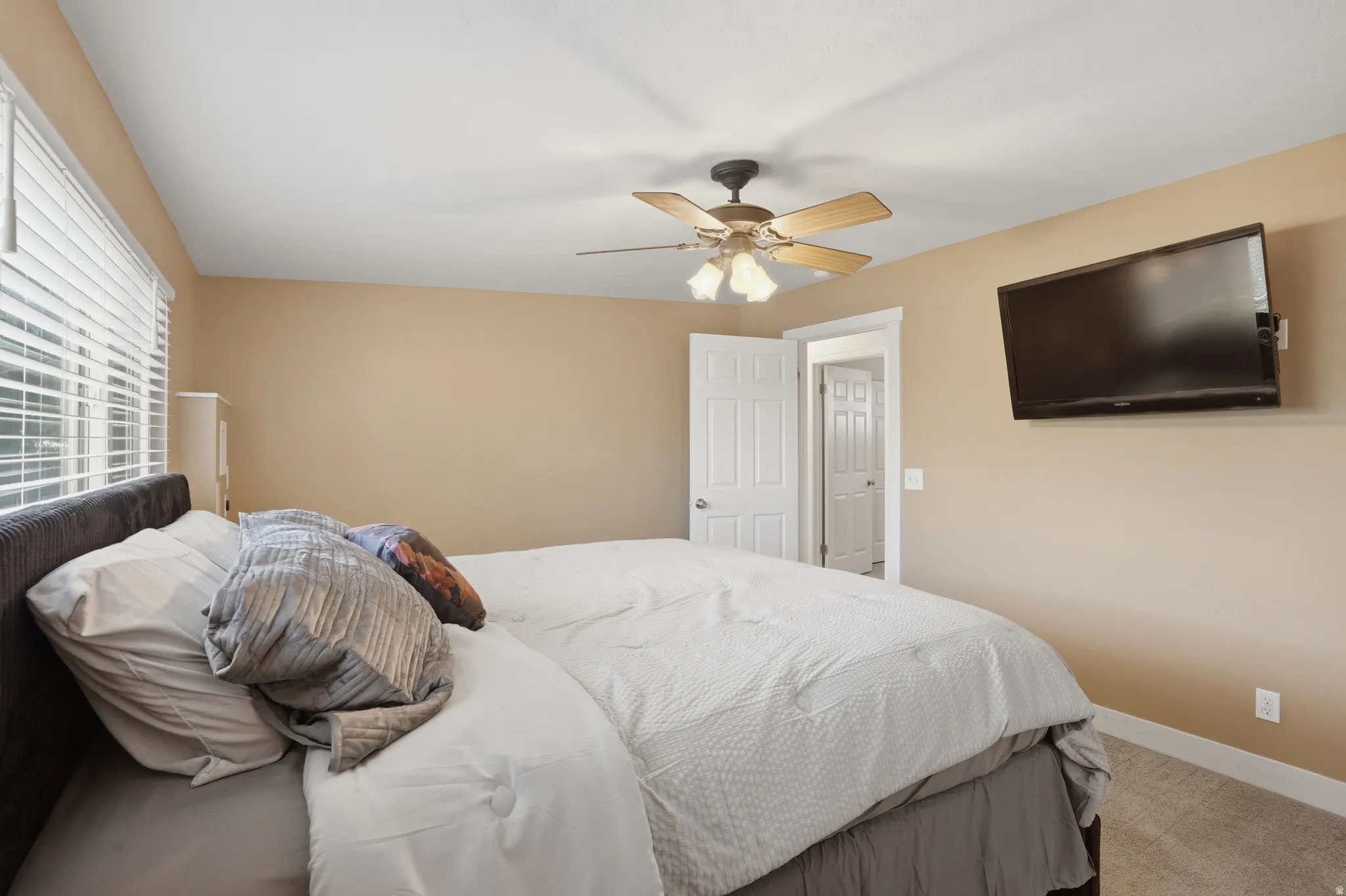 Spacious room featuring carpeting, neutral wall tones, and a ceiling fan with integrated lighting