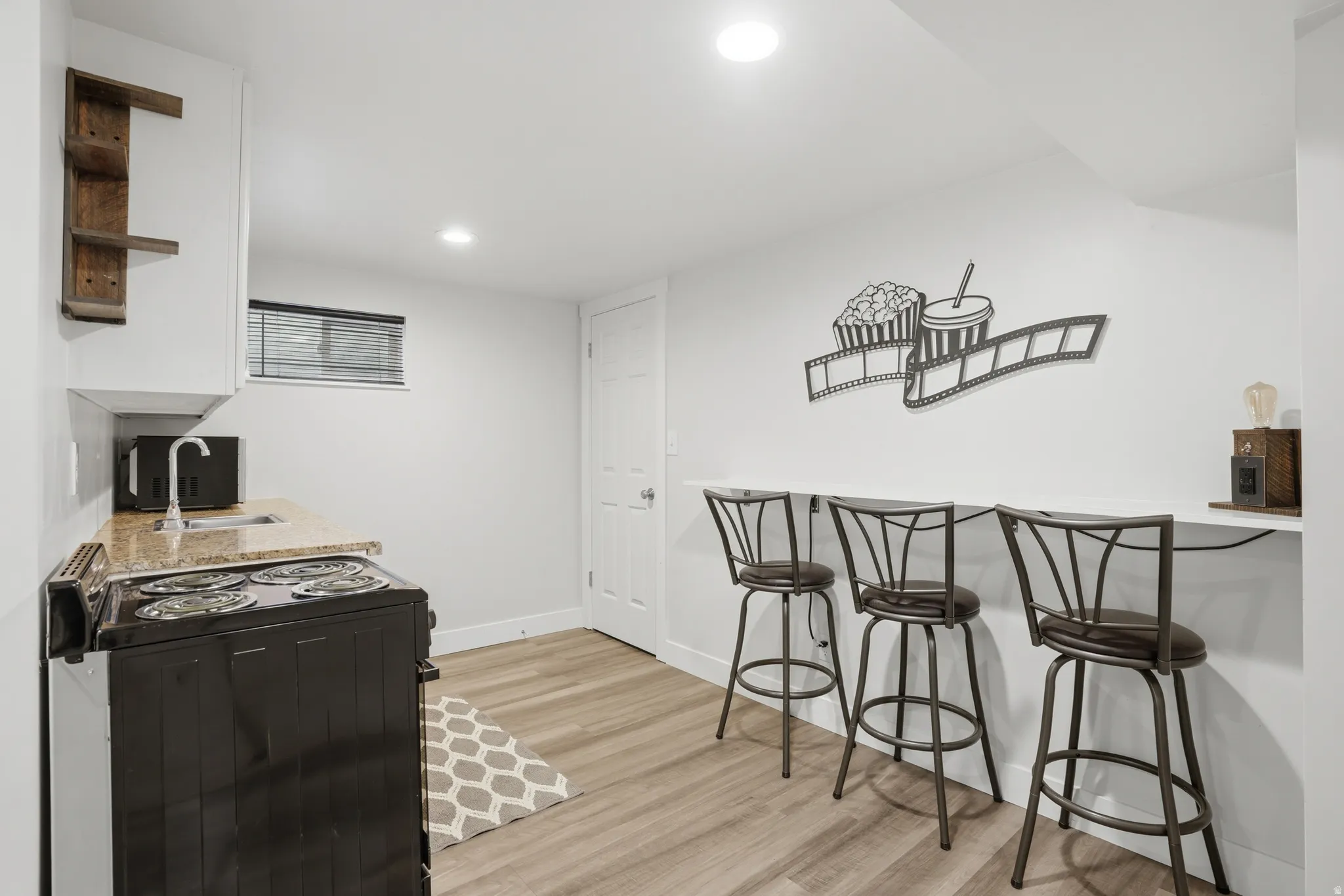 Kitchenette featuring an electric range, stainless steel sink, and light-toned countertop