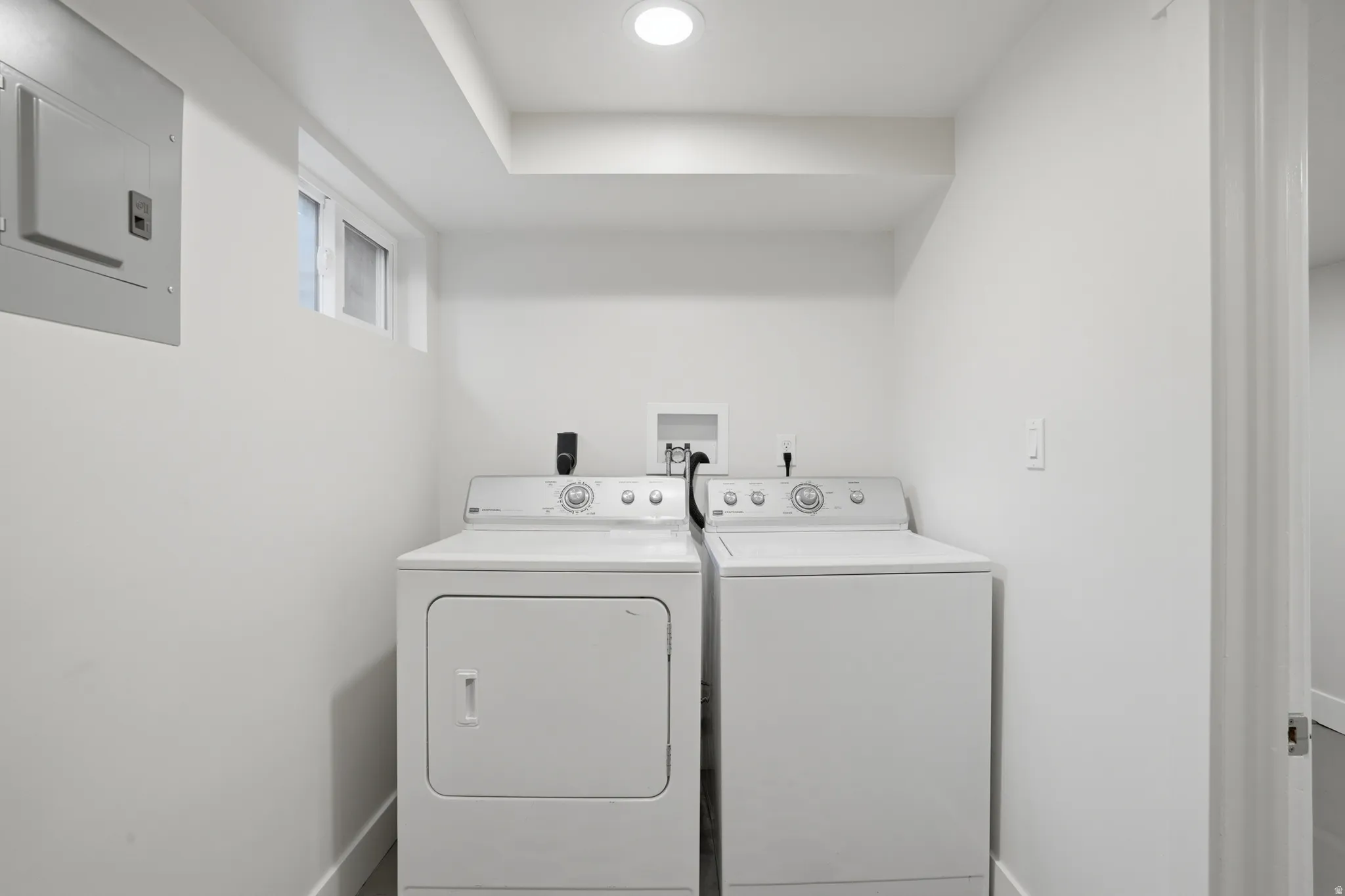 Dedicated laundry area featuring a white washer and dryer, recessed lighting, and a horizontal window