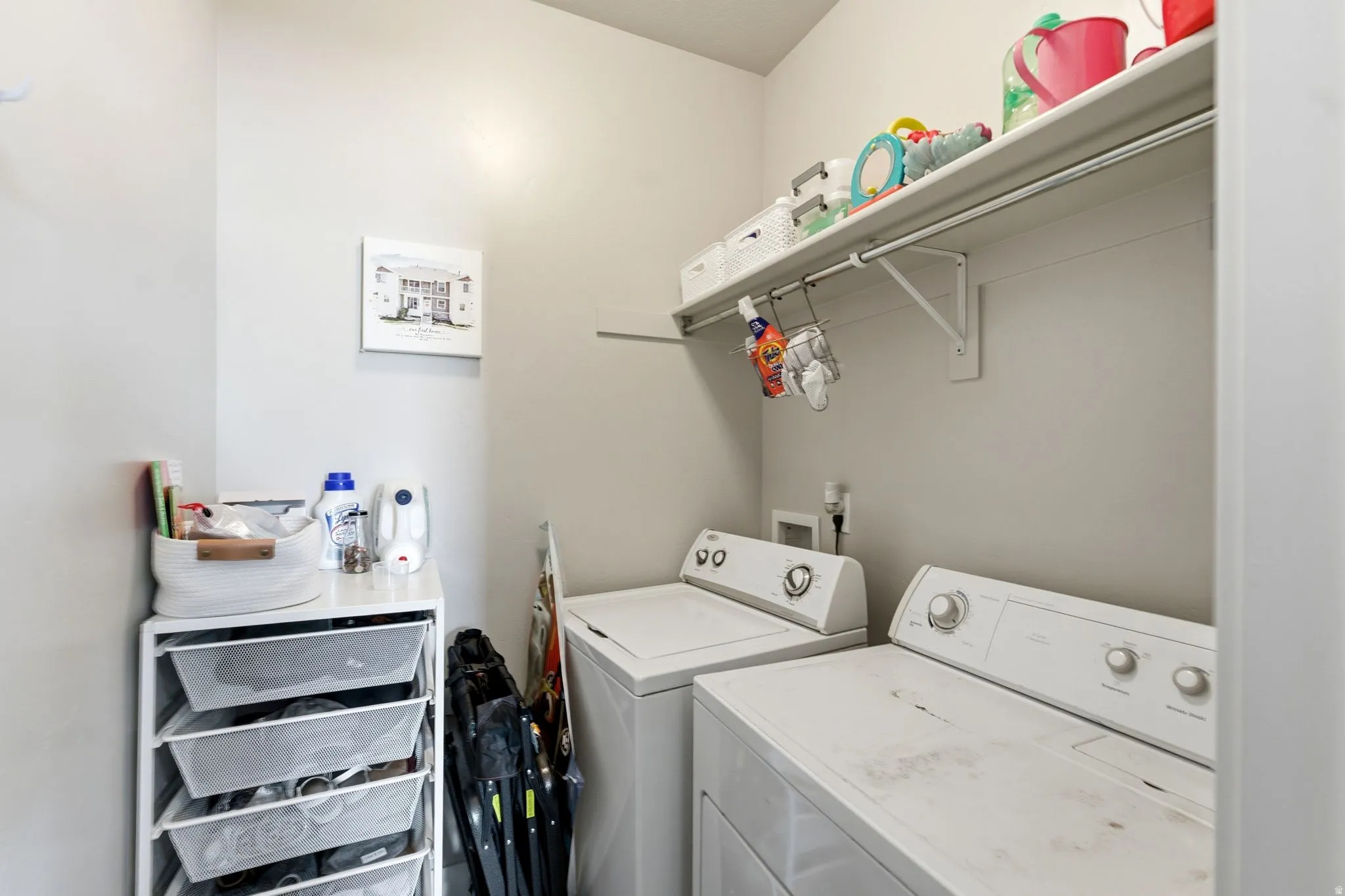 Dedicated laundry area featuring a shelf, hanging rod, and light gray walls