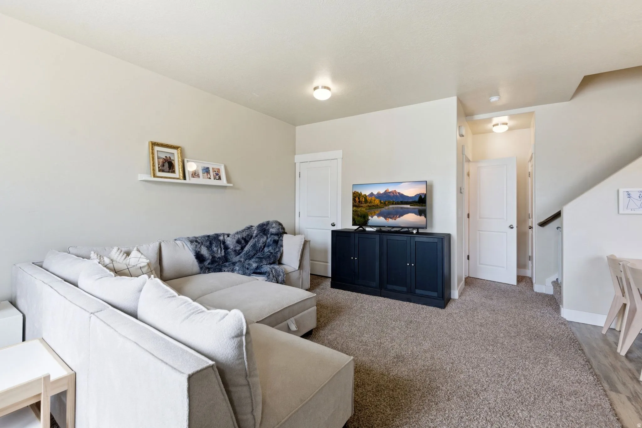Carpeted living area featuring light-toned walls, recessed lighting, and a built-in media cabinet