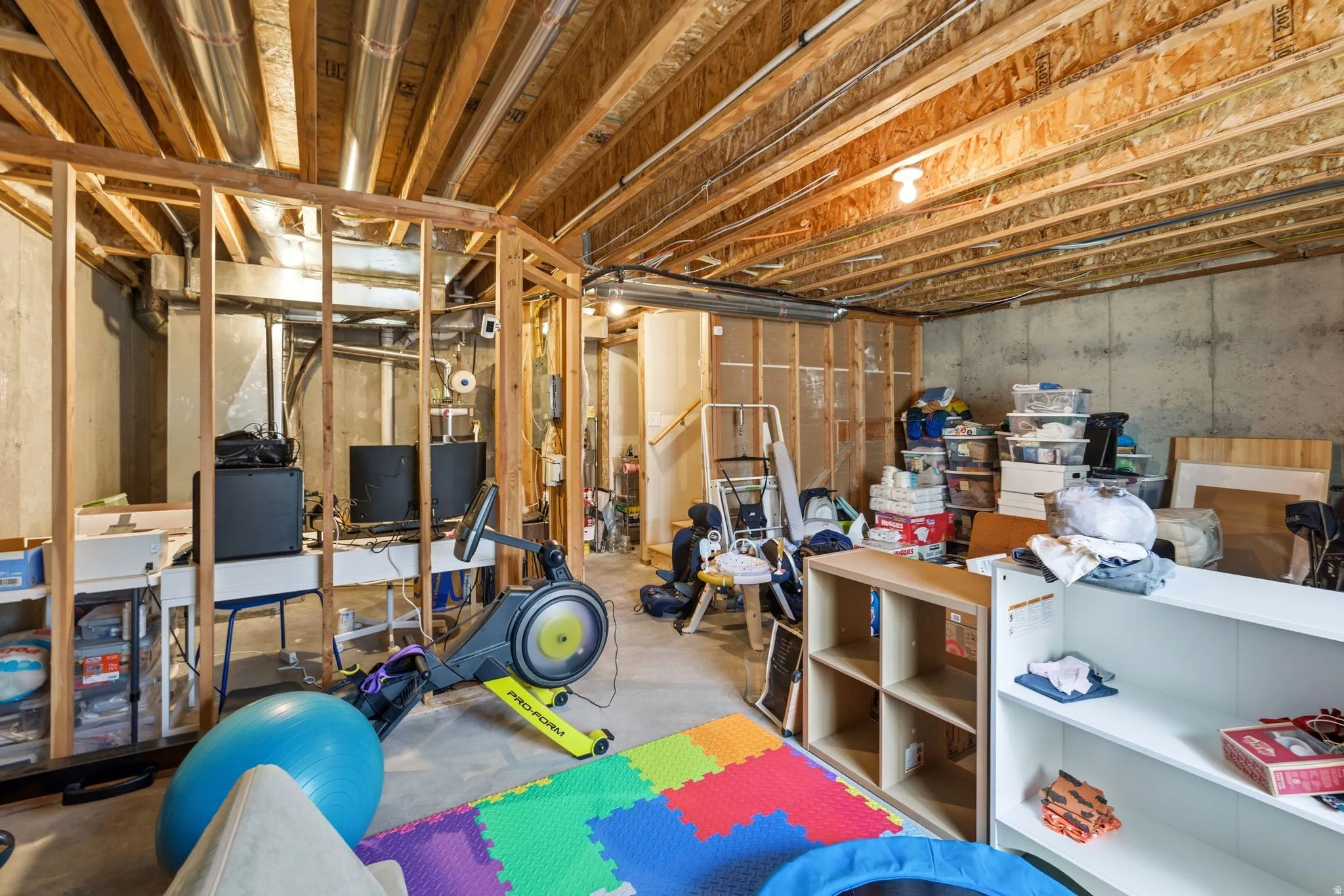 Unfinished basement featuring exposed wood joists and concrete walls, providing a versatile space for customization