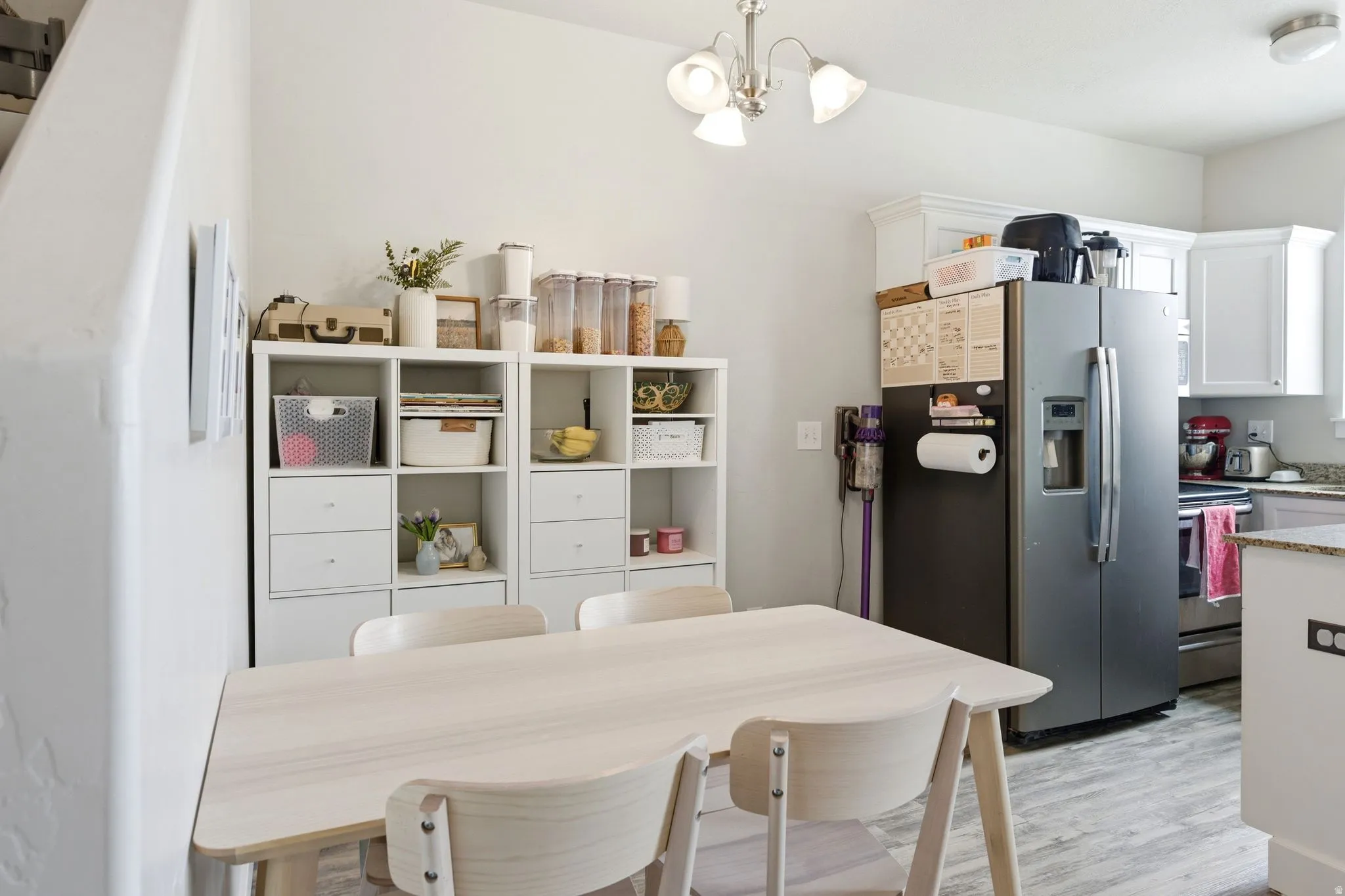 Kitchen area featuring white cabinetry, granite-style countertops, and wood-finish flooring