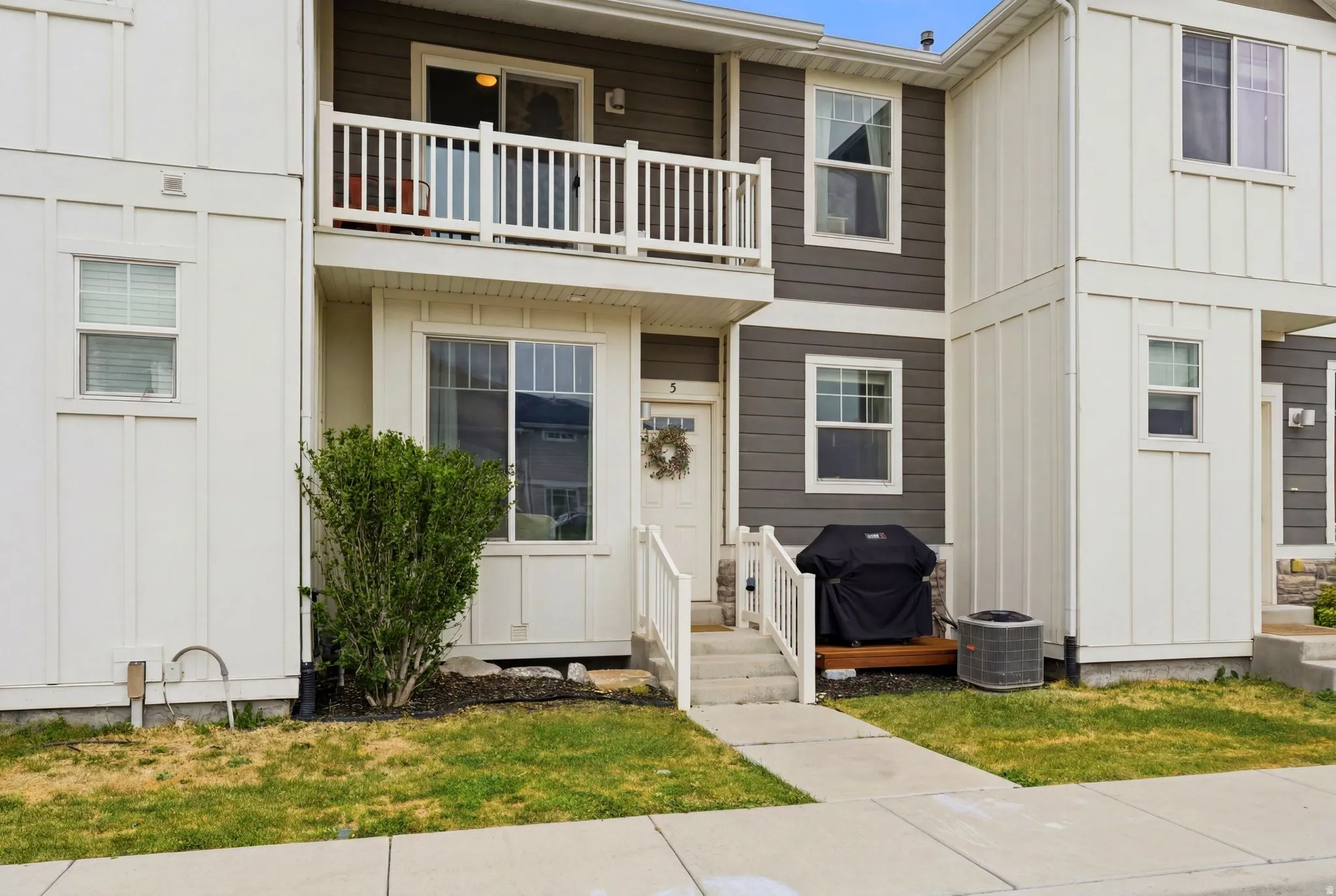 Modern townhome exterior featuring a two-tone facade with white board-and-batten siding and horizontal dark gray siding