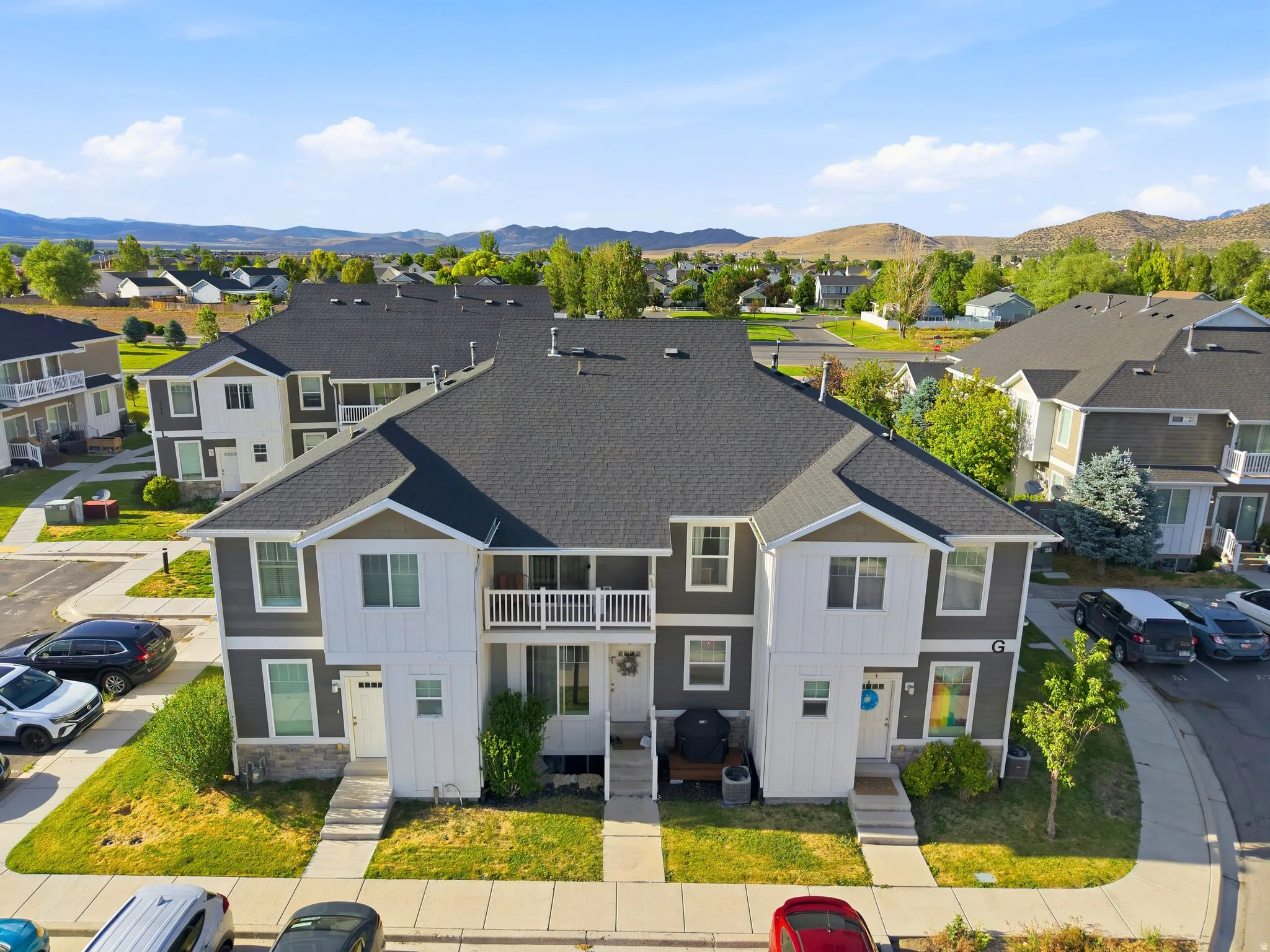 Modern duplex exterior featuring a dark gray roofline, white siding accents, and complementary dark gray lower siding