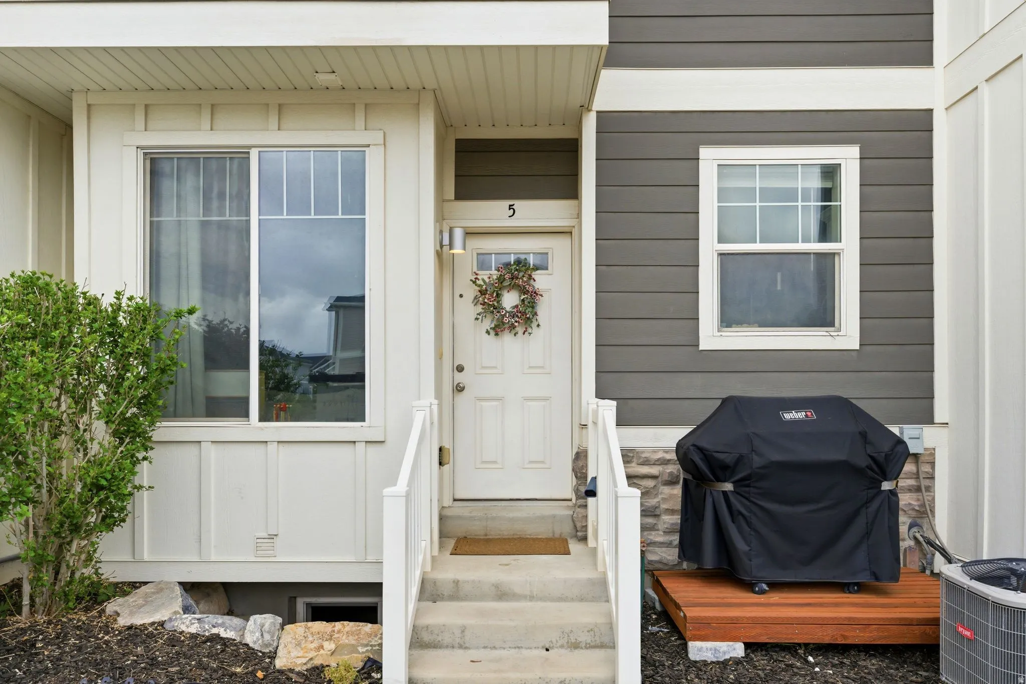 Entryway featuring a white door with an overhead light fixture, concrete steps with white railings, and an adjacent window with white trim