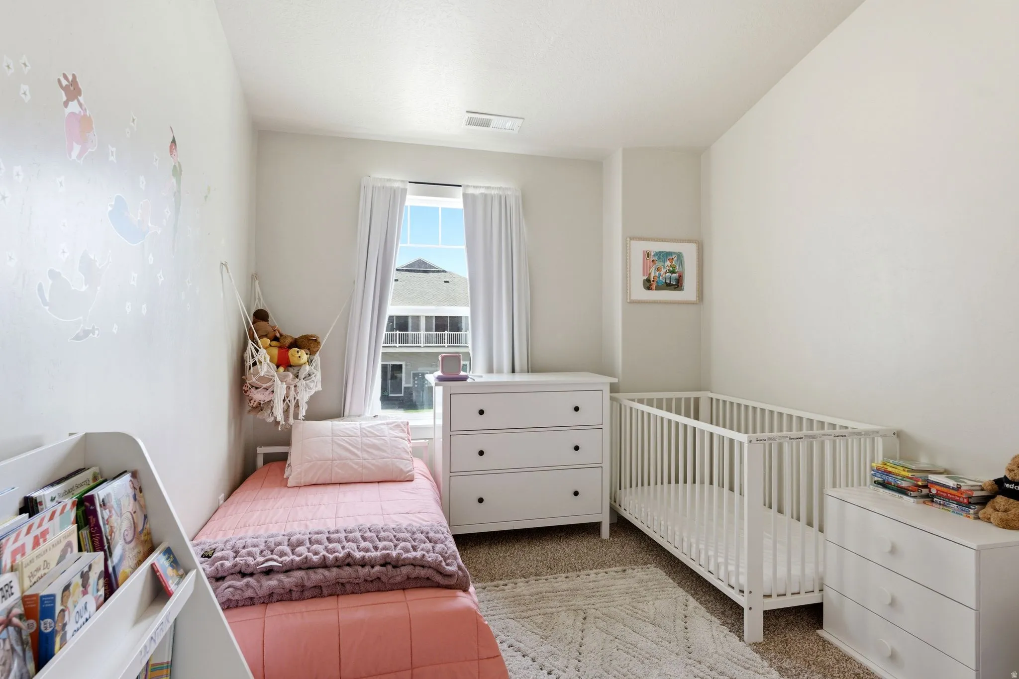 Bright bedroom featuring neutral wall tones, a large window, and carpet flooring
