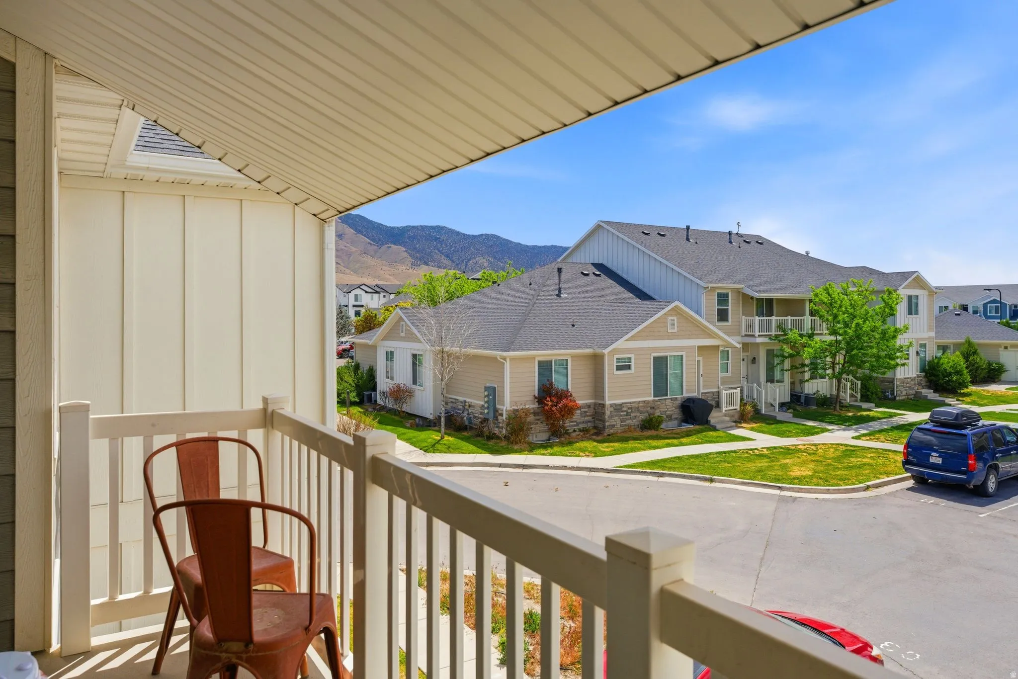Covered balcony with white railing, offering elevated views of the residential area