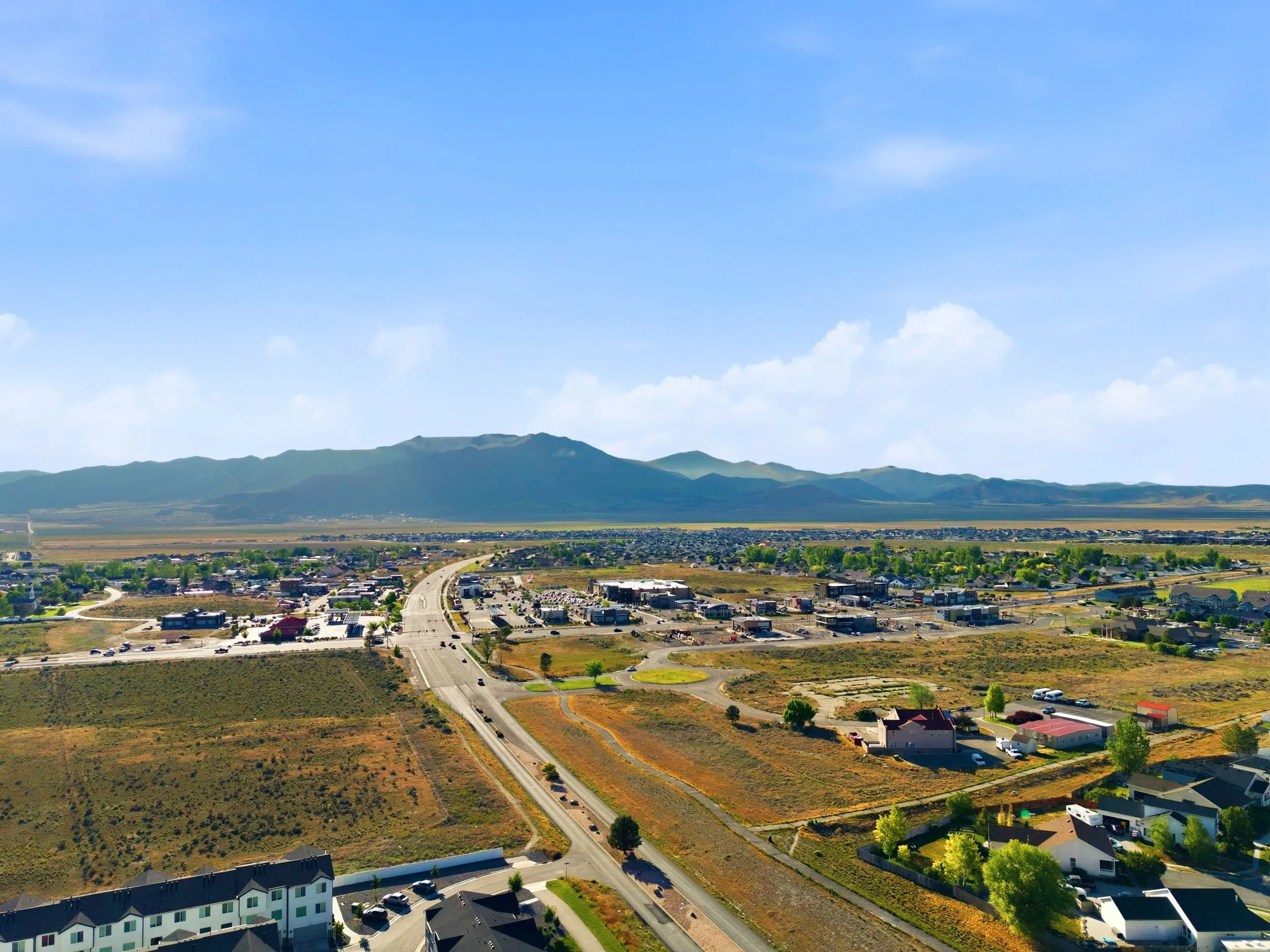 Expansive aerial capturing a road system traversing an urban landscape with visible commercial and residential buildings