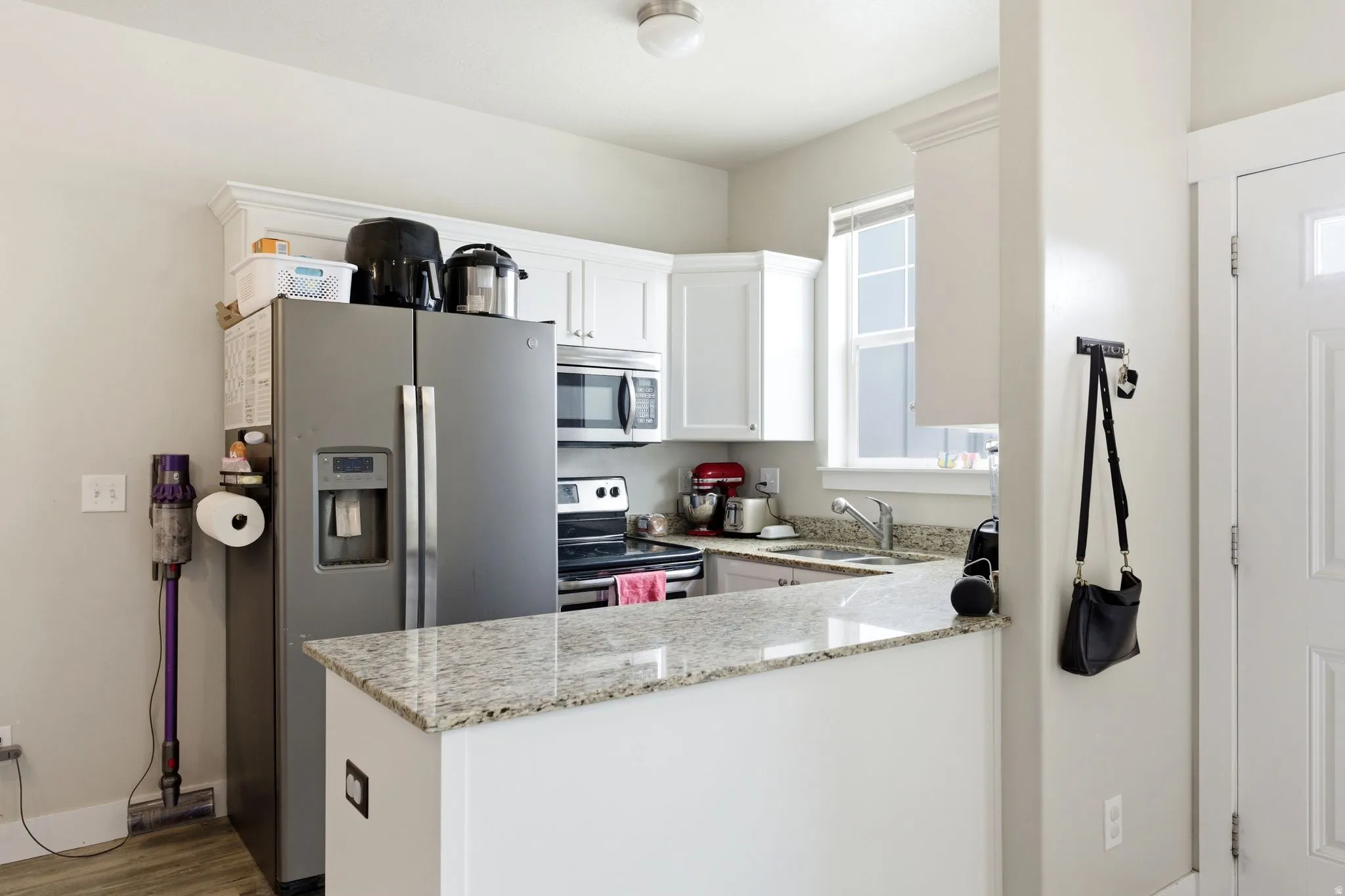 Kitchen featuring white cabinetry, light-colored granite countertops, and stainless steel appliances