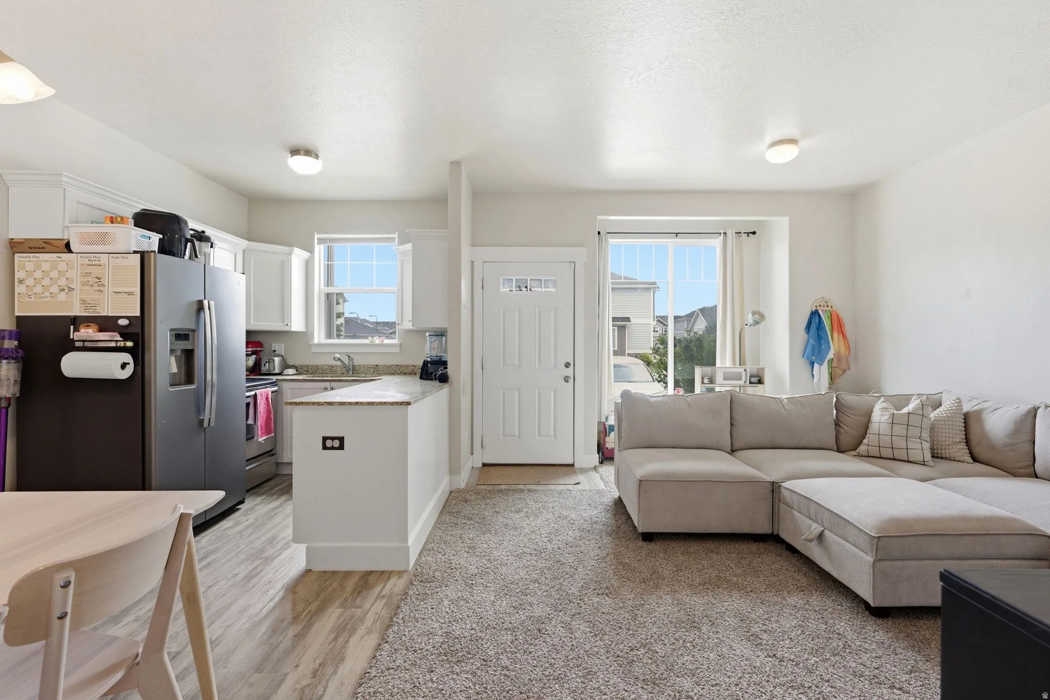 Open-concept living area featuring a kitchen with white cabinetry, light-toned countertops, and wood-finish flooring