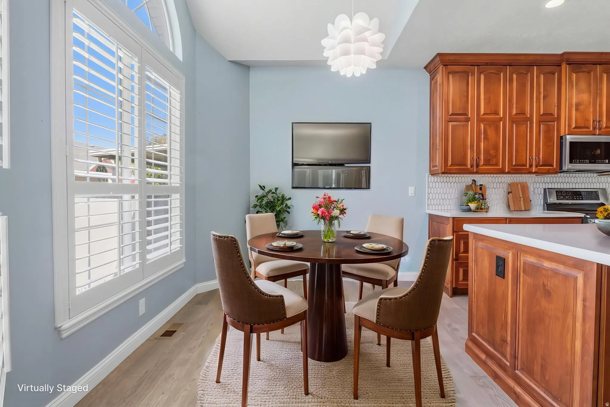 Virtually Staged: Breakfast nook with plantation shutters and arched upper window, featuring wood-finish flooring