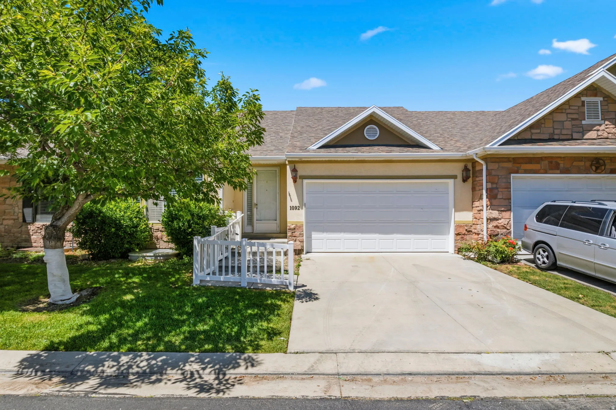 Exterior featuring a two-car garage, concrete driveway, and a front yard with established landscaping
