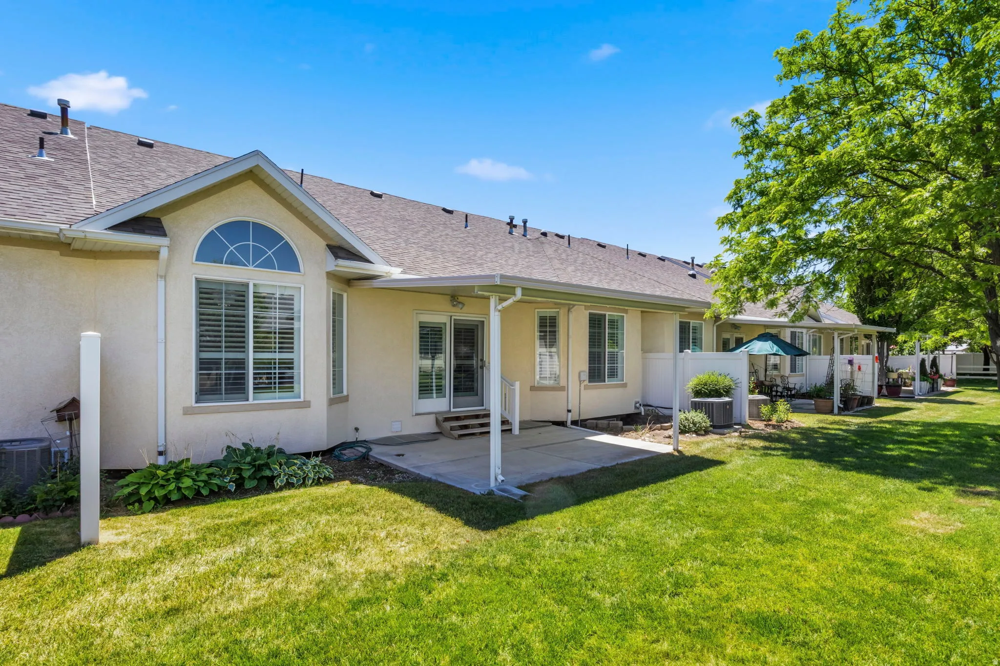 Exterior stucco finish with a prominent bay window featuring an arched transom, ground-level patio, and sliding glass doors