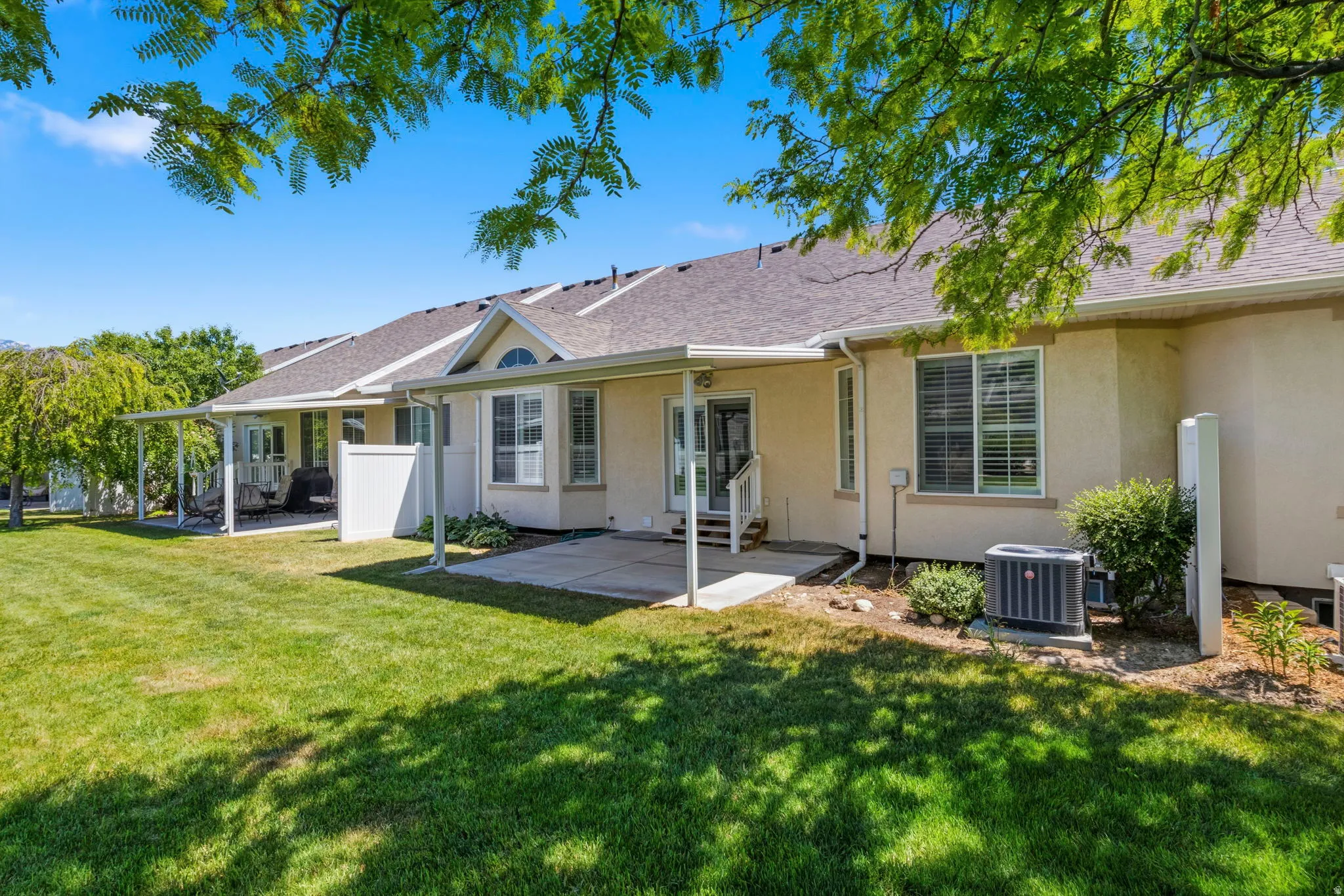 Expansive green lawn with mature trees providing dappled shade