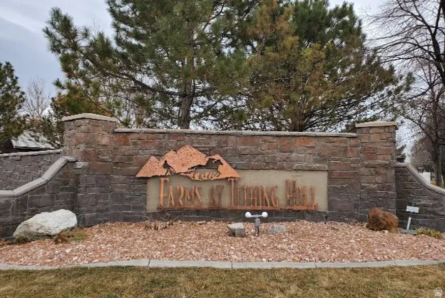 Stone retaining wall featuring a metal-cut sign, surrounding a landscape bed with decorative gravel and natural boulders