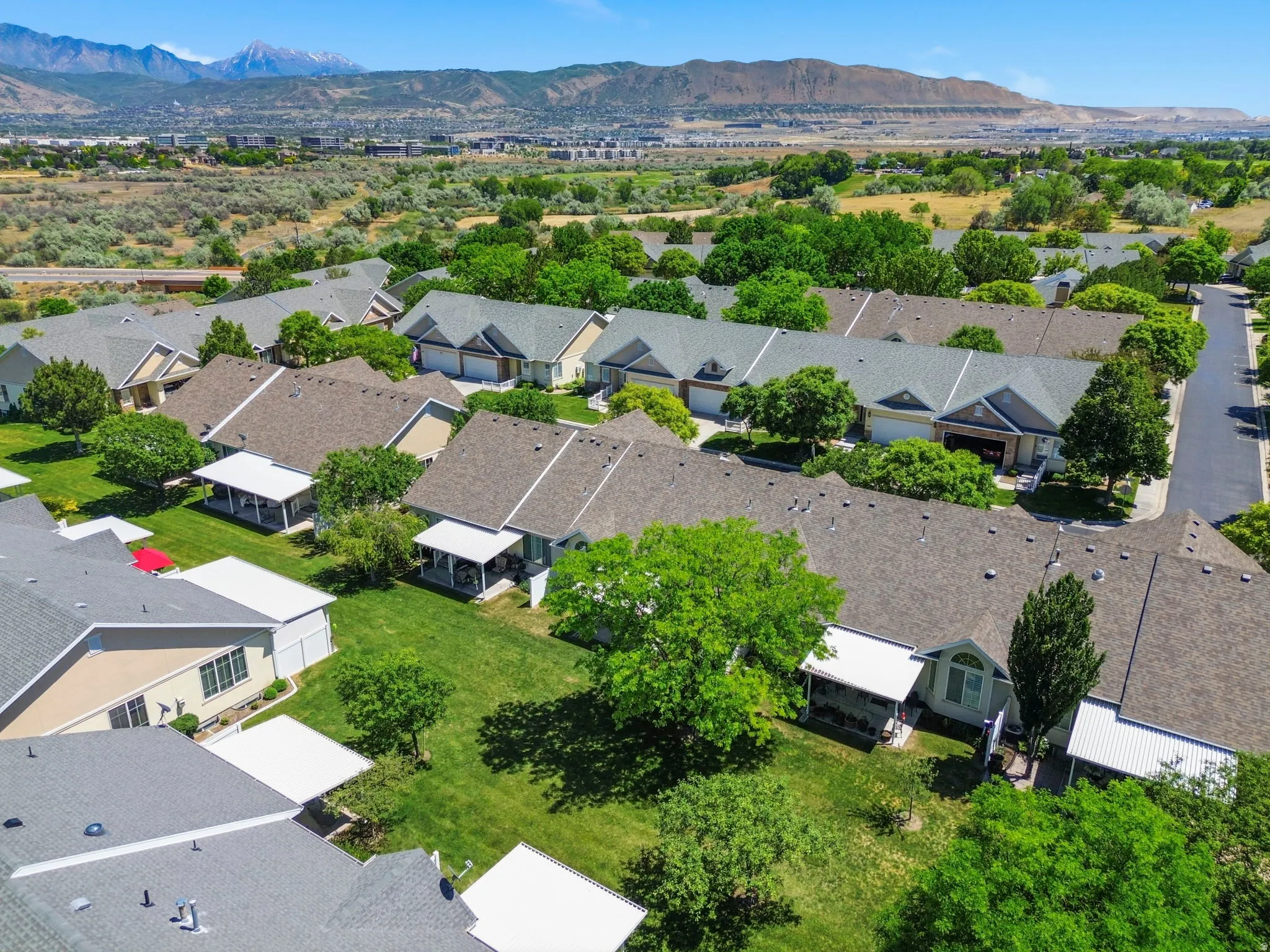 Residential development featuring a mountain backdrop, mature trees, and a paved street