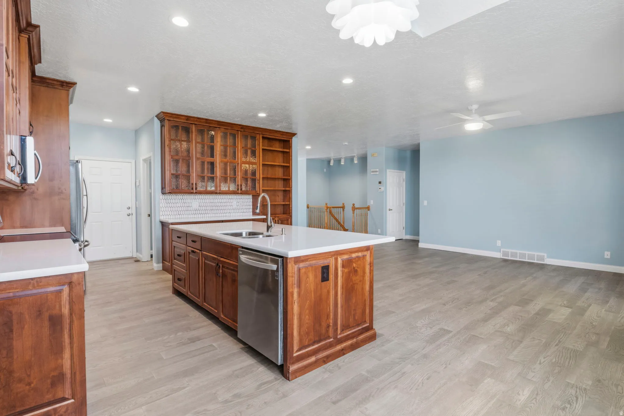 Kitchen island with white countertop, integrated stainless steel sink, and stainless steel dishwasher