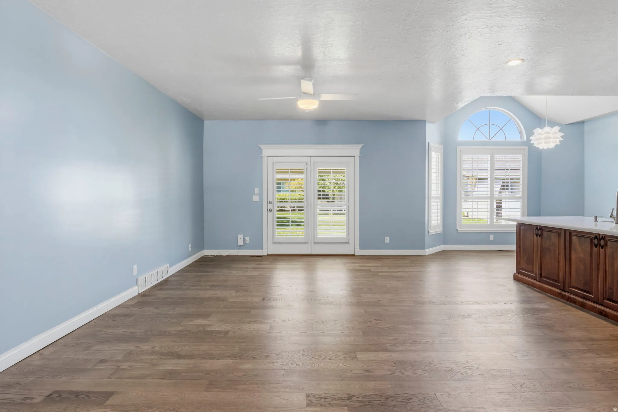 Spacious room featuring wood-finish flooring, white baseboards, and light blue walls