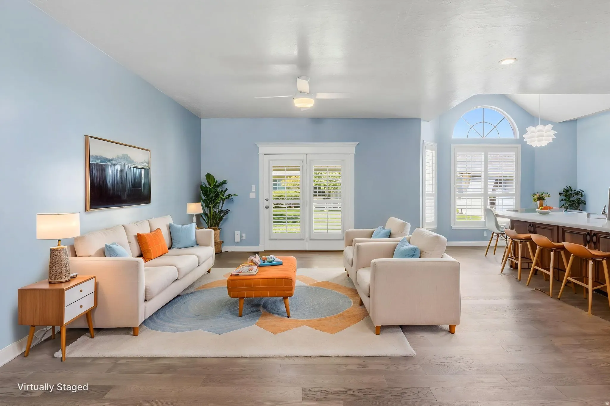 Virtually Staged: Spacious living area featuring wood-finish flooring, vaulted ceilings, and light blue walls